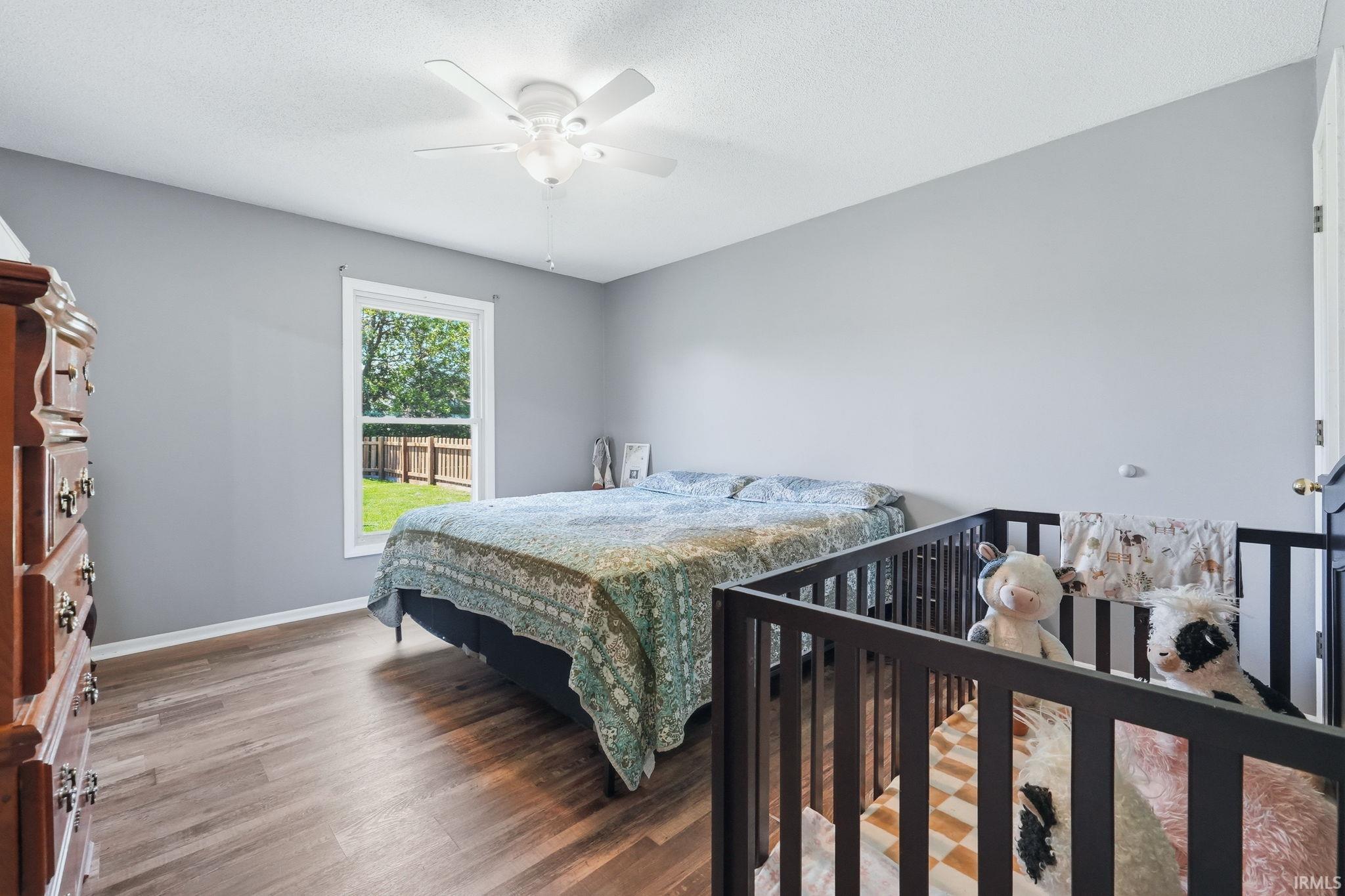 Bedroom featuring wood-finish flooring, a white ceiling fan, and light gray walls