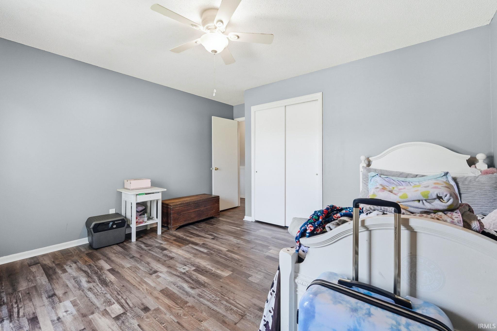 Spacious room with wood-finish flooring, light grey walls, and a ceiling fan