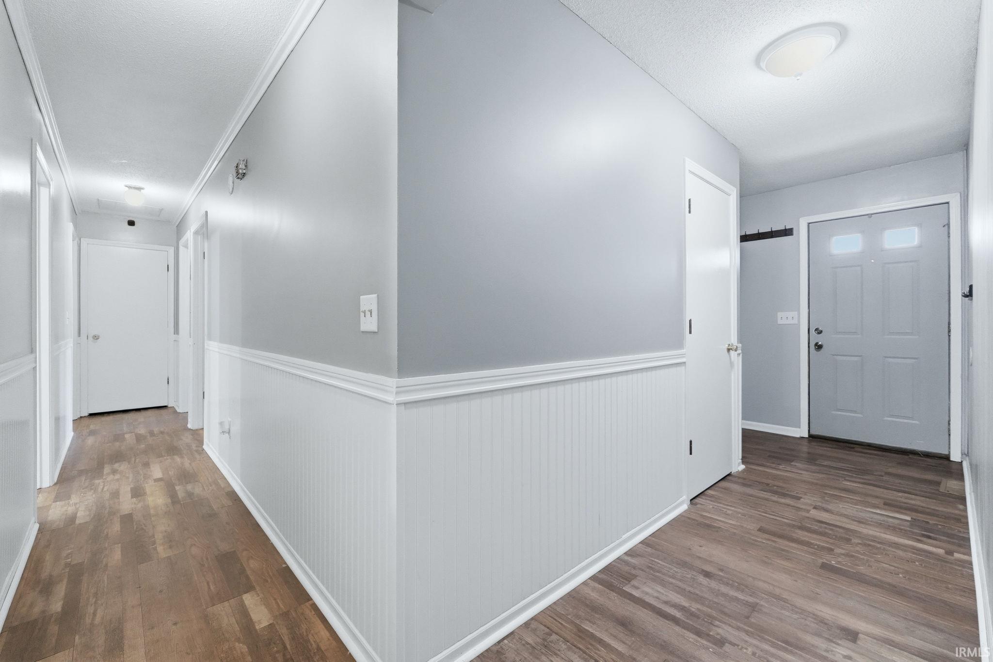 Entryway featuring wood-finish flooring, beadboard wainscoting, and a paneled front door with upper glass inserts