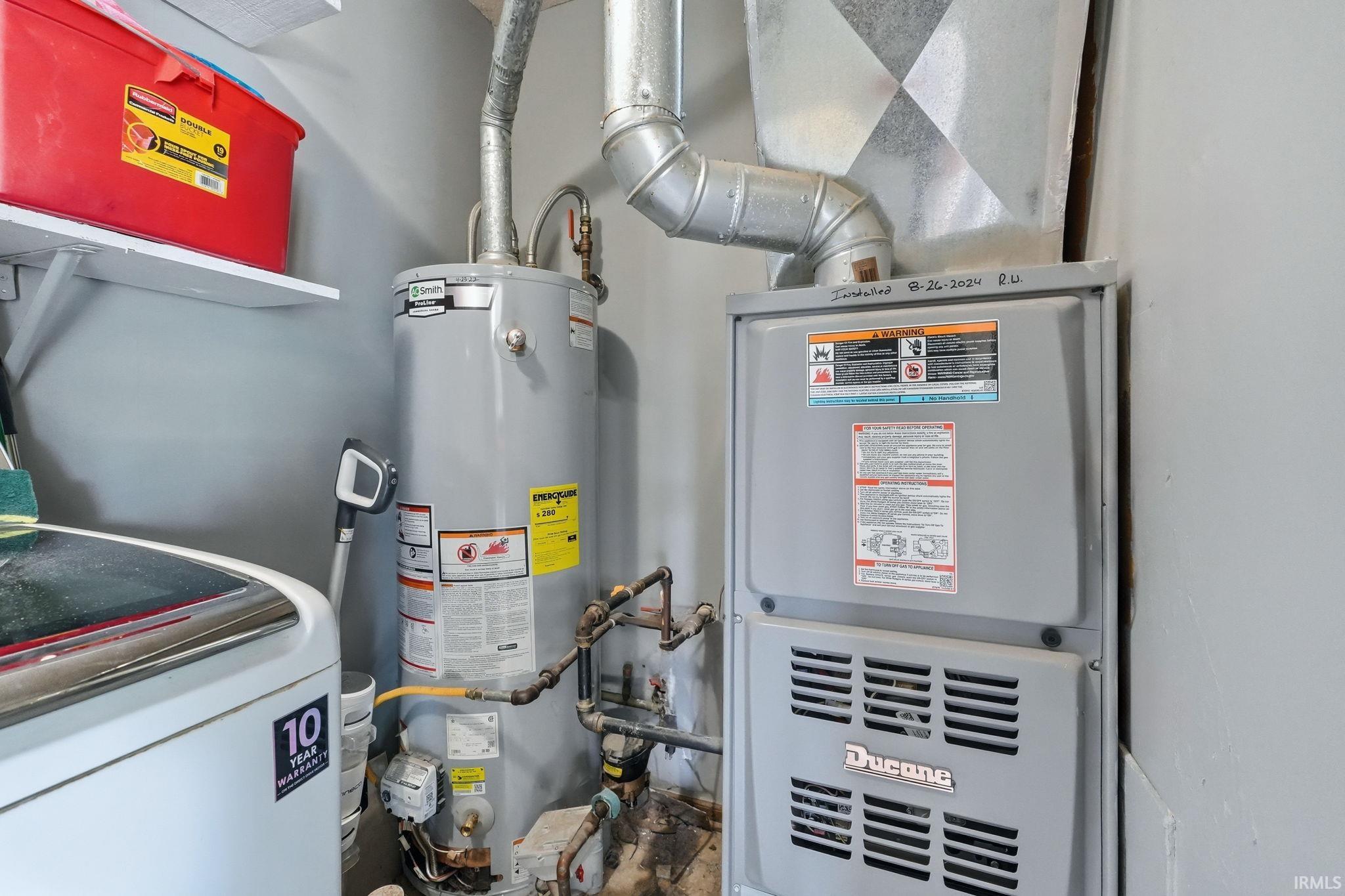 Dedicated utility area featuring a water heater, furnace, and a portion of a top-loading washing machine