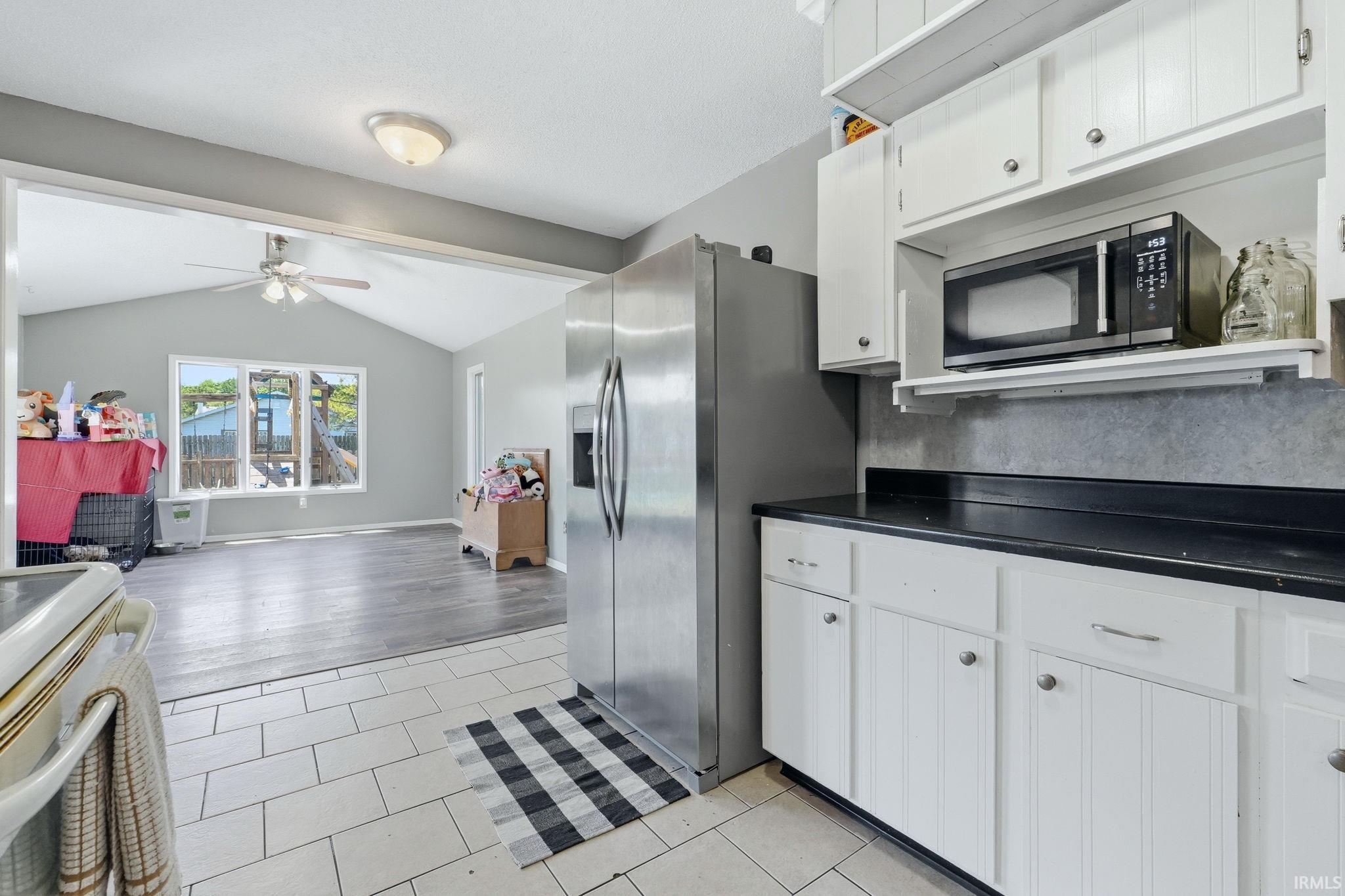 Kitchen featuring white cabinetry, dark countertops, and tile flooring