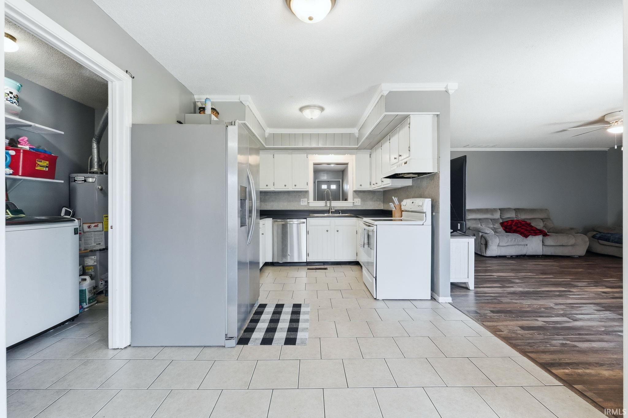 Kitchen featuring light-colored tile flooring, white cabinetry, and stainless steel appliances including a refrigerator and dishwasher