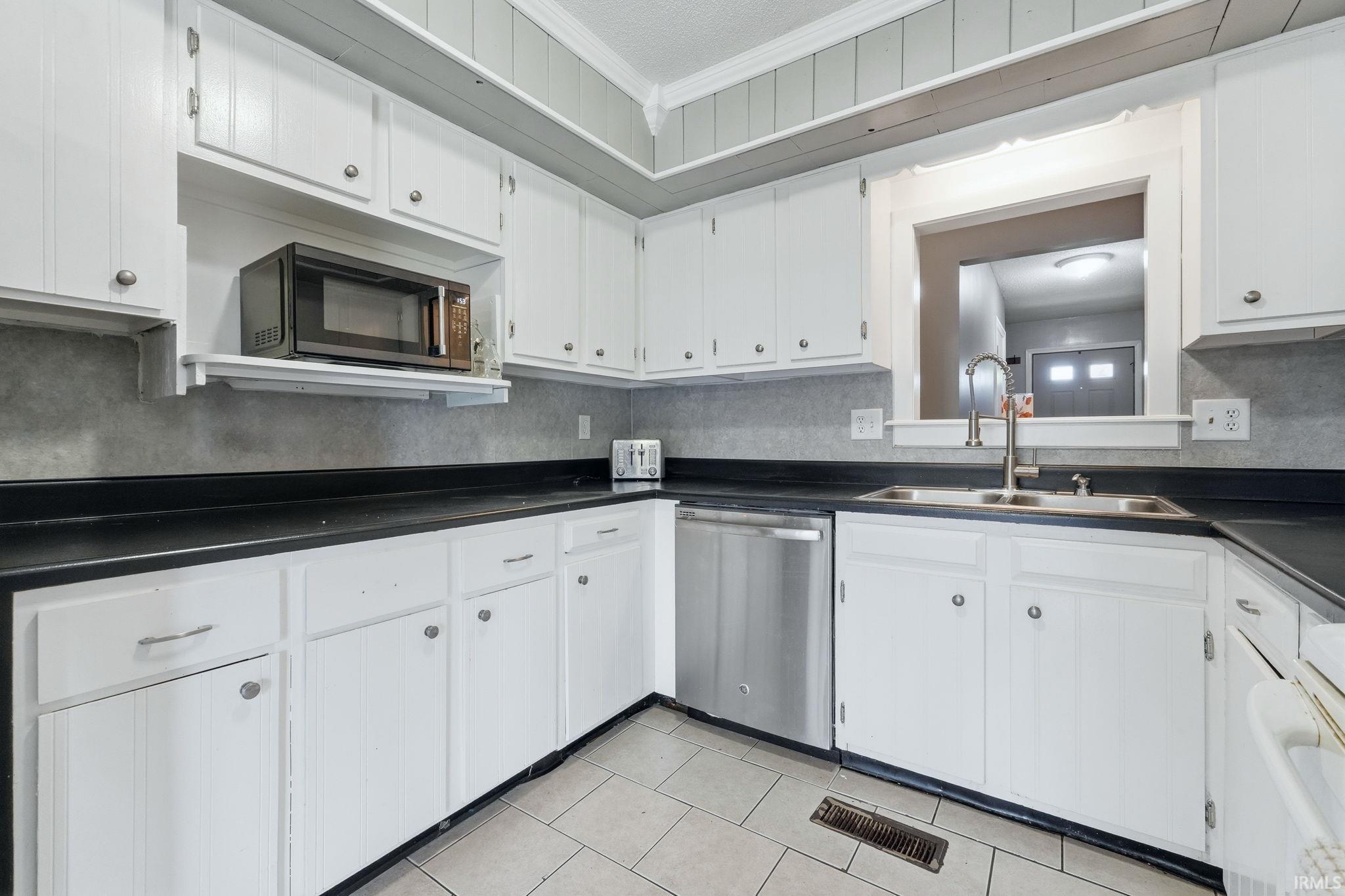 Kitchen with white cabinetry, dark countertops, and a dual basin stainless steel sink