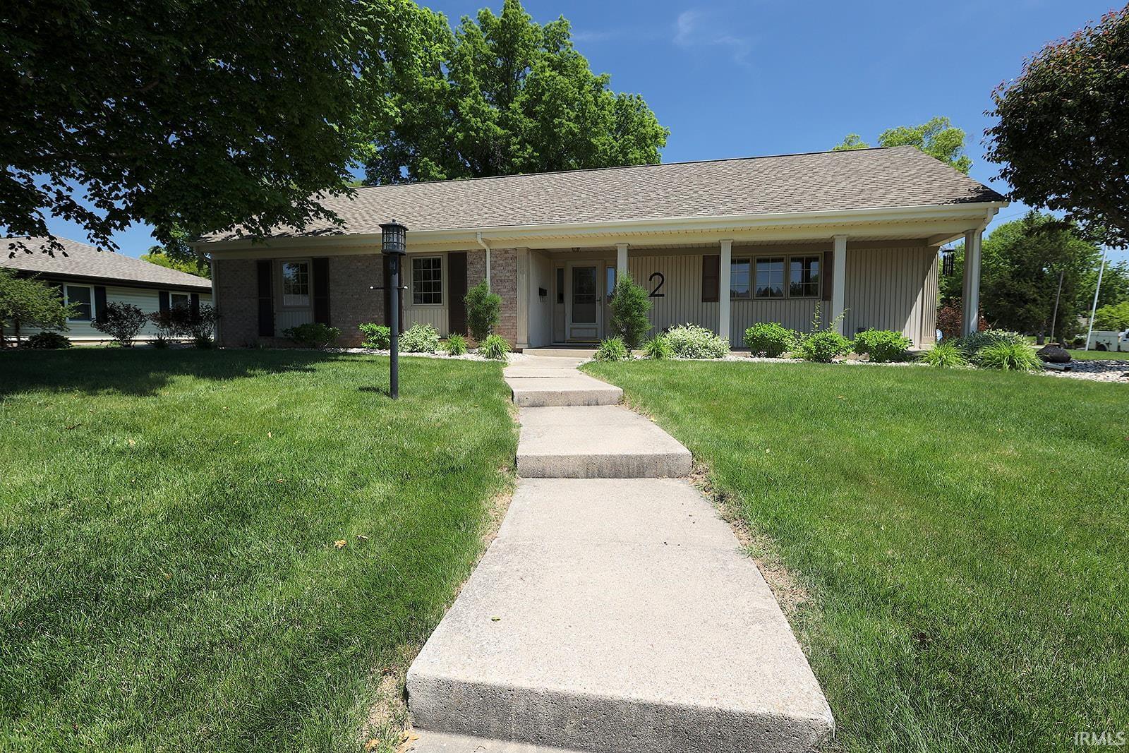 Ranch-style exterior featuring a covered entry, light-colored siding, and a dark shingled roof