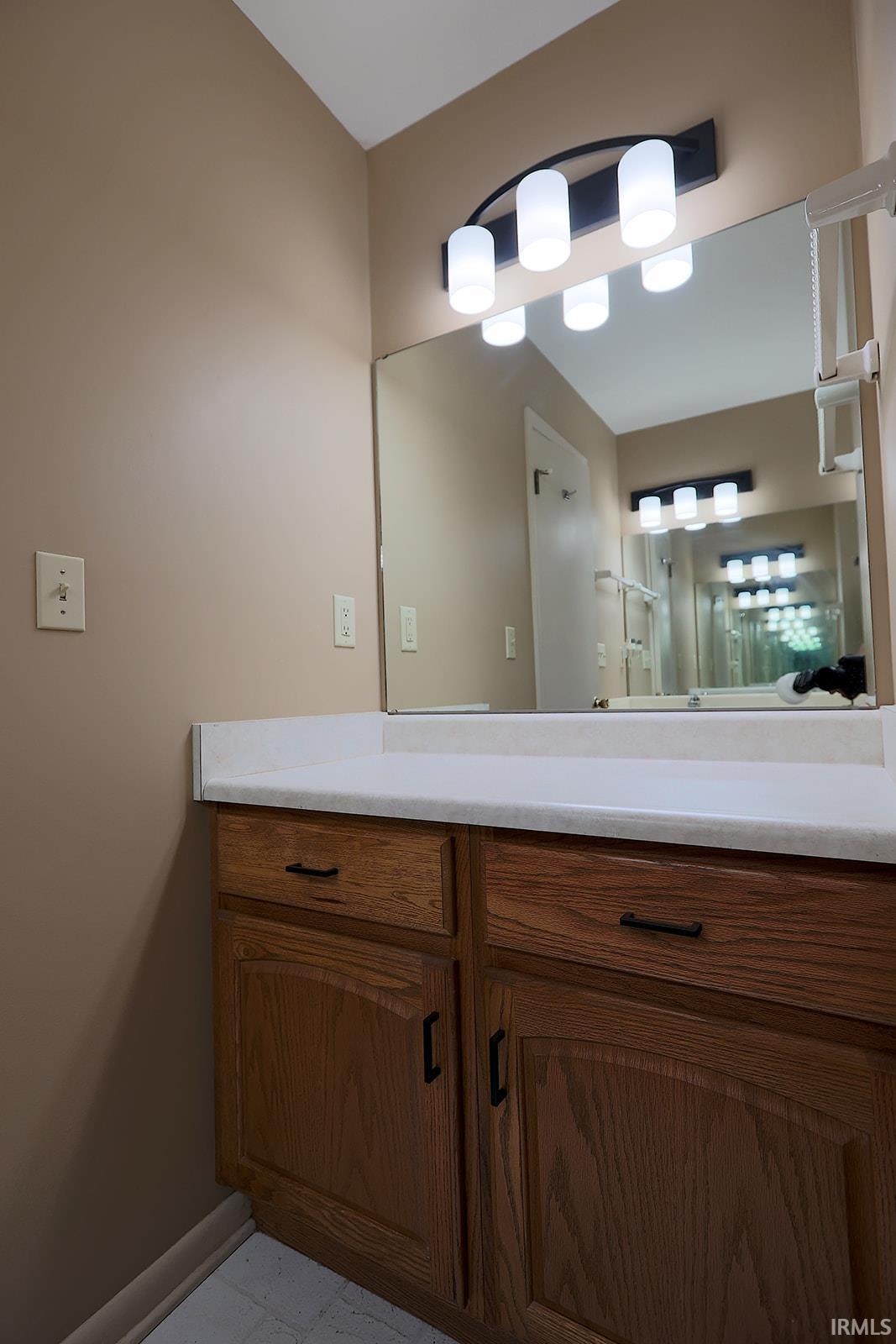 Bathroom vanity featuring wood cabinetry, a light countertop, and a wide mirror