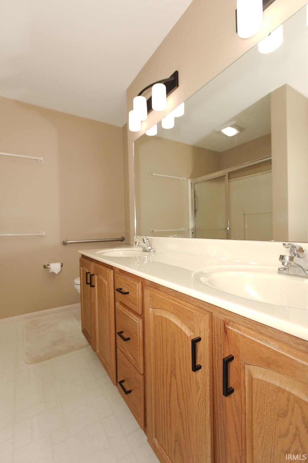 Double vanity with dual undermount sinks, wood-finish cabinetry, and matte black hardware