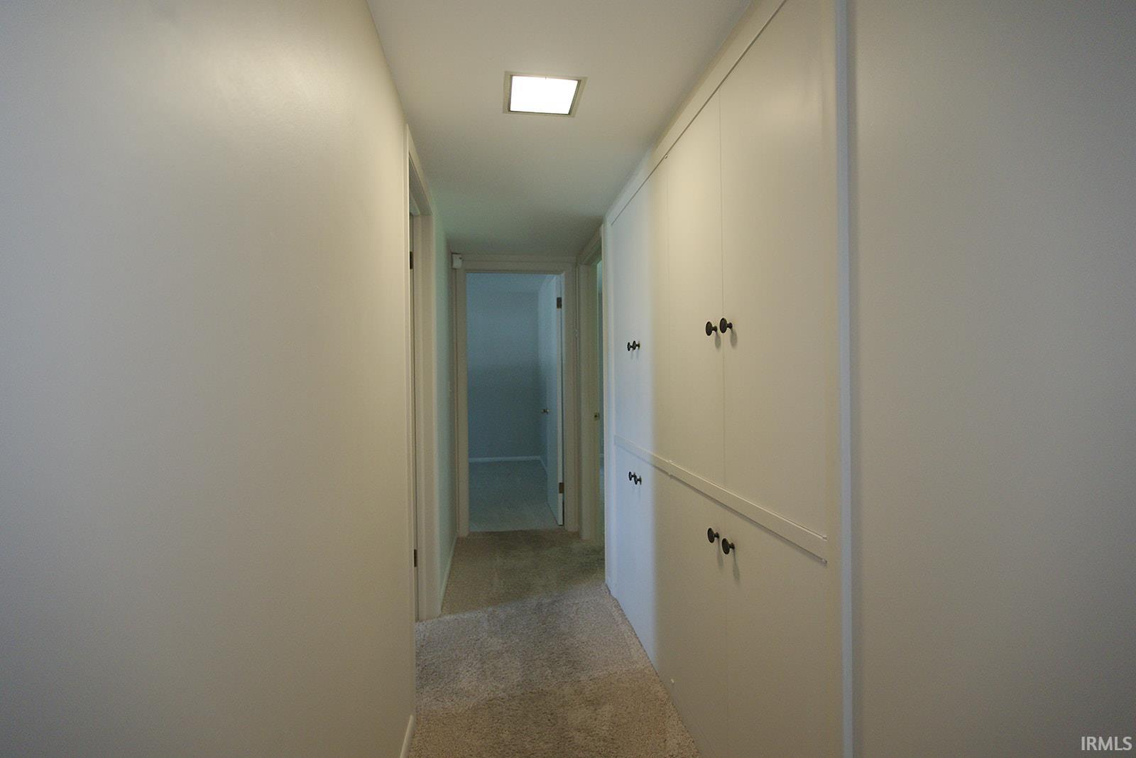 Hallway featuring a built-in storage system with white cabinetry and dark hardware