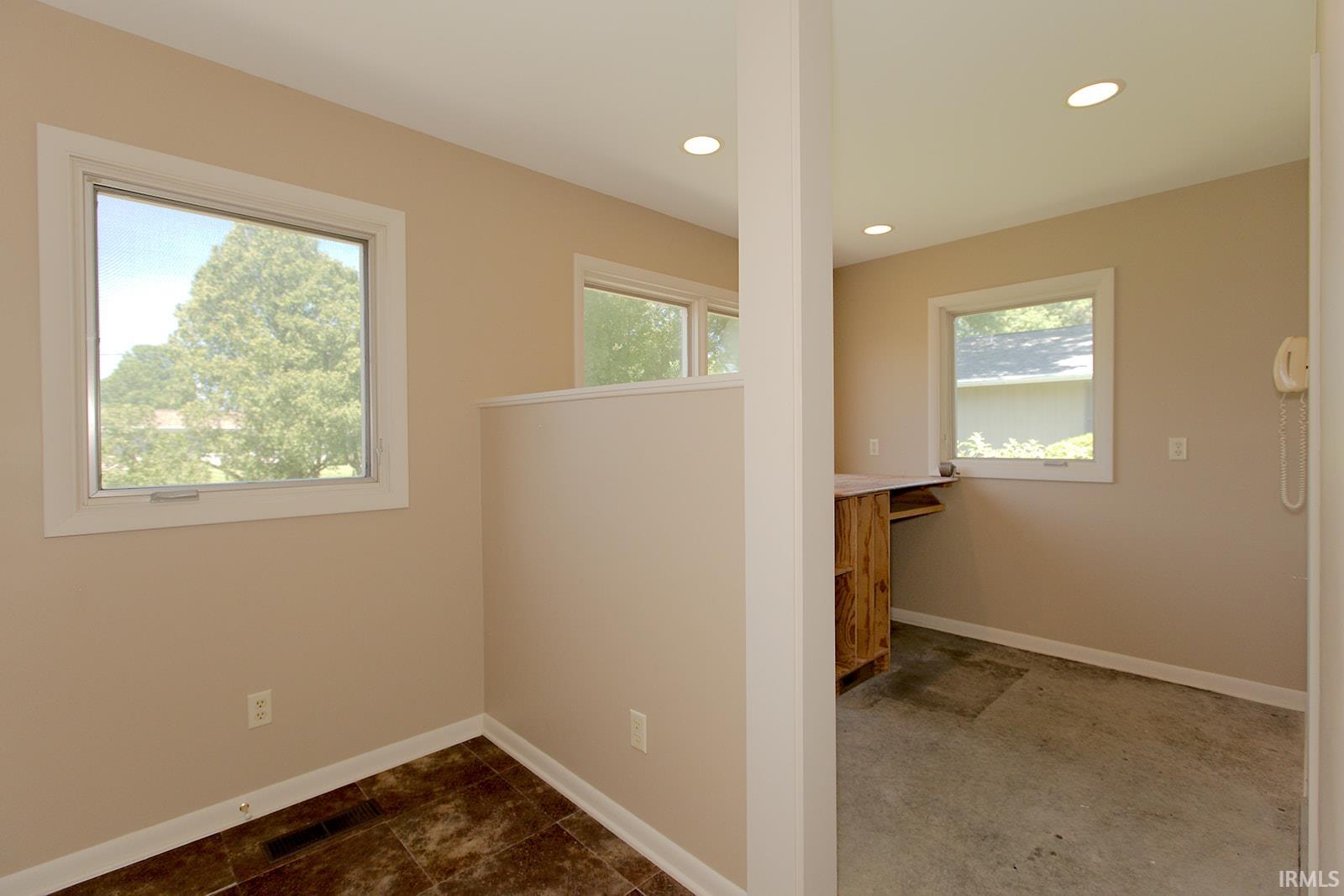 Versatile interior space featuring multiple windows, recessed lighting, and a partial wall separation