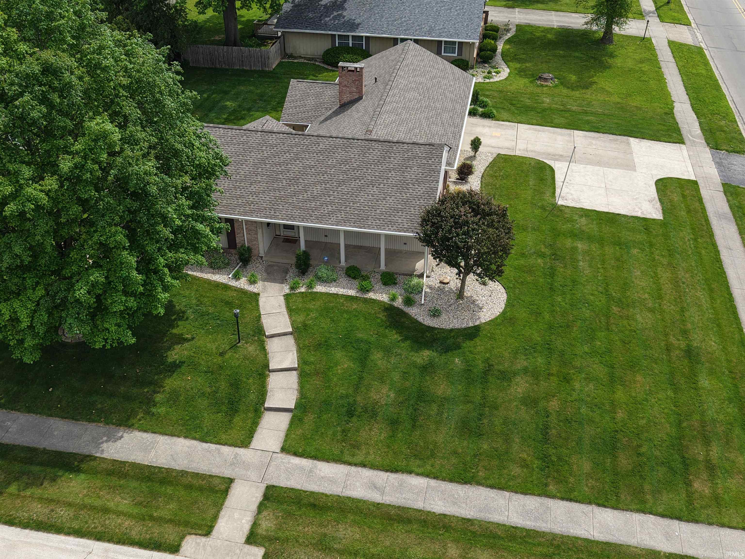 Aerial perspective showcasing a single-story residence with a covered front porch and a multi-pitched roofline