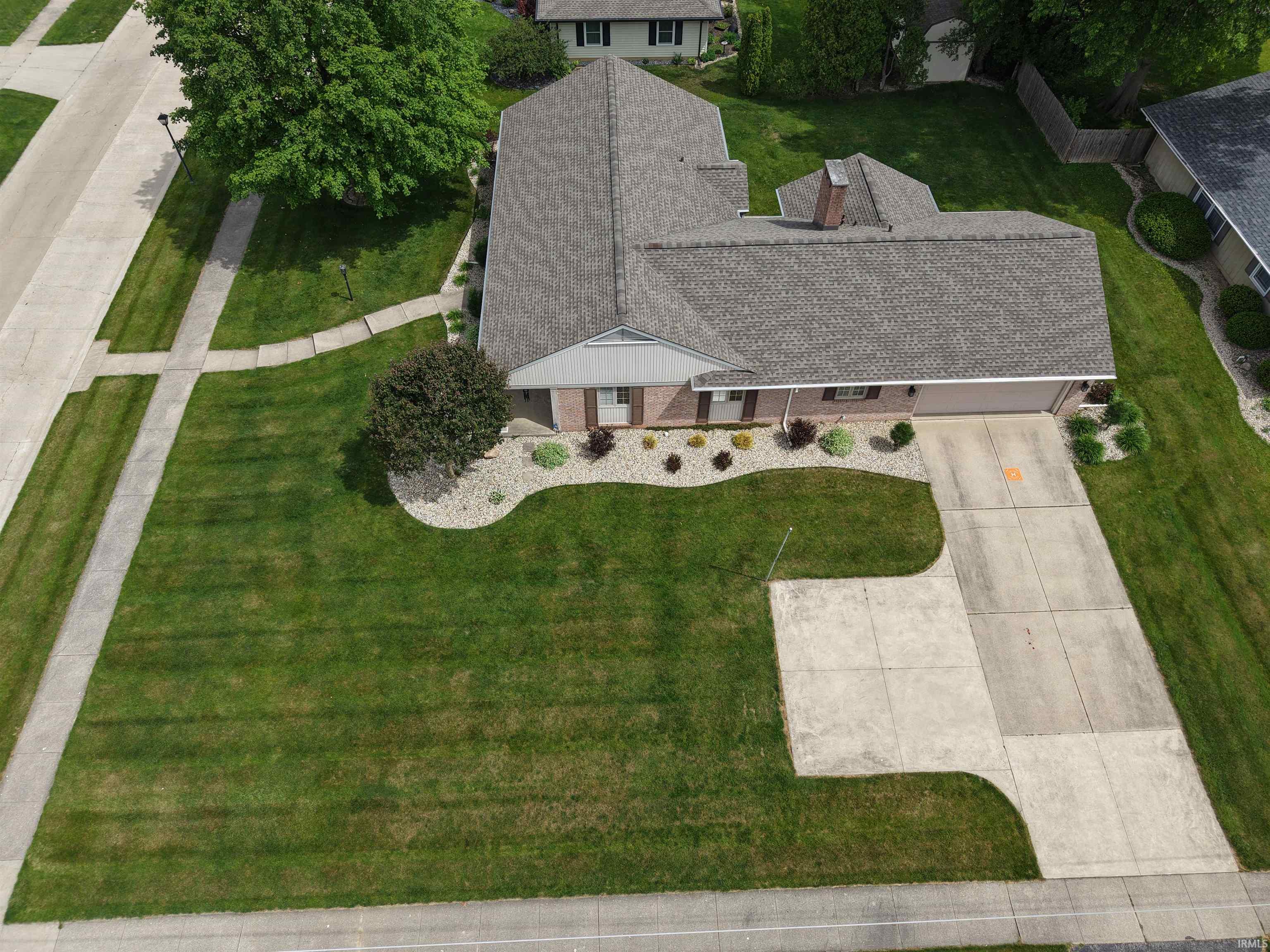Brick facade residence featuring a two-car garage, concrete driveway, and a shingled roof
