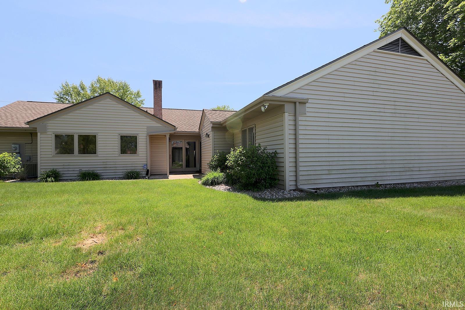 Expansive lawn area surrounding a multi-level structure featuring light-colored siding, a brown shingle roof, and a visible chimney