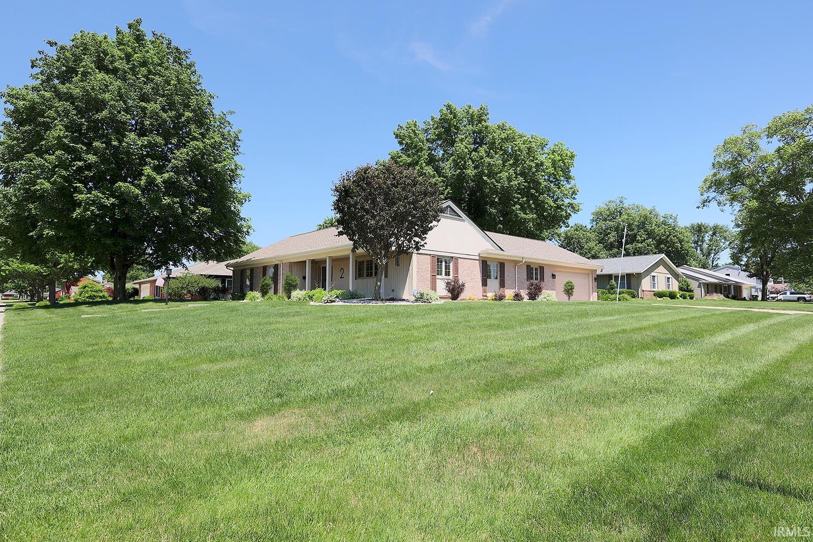 Spacious front lawn with mature shade trees and a welcoming covered porch entry