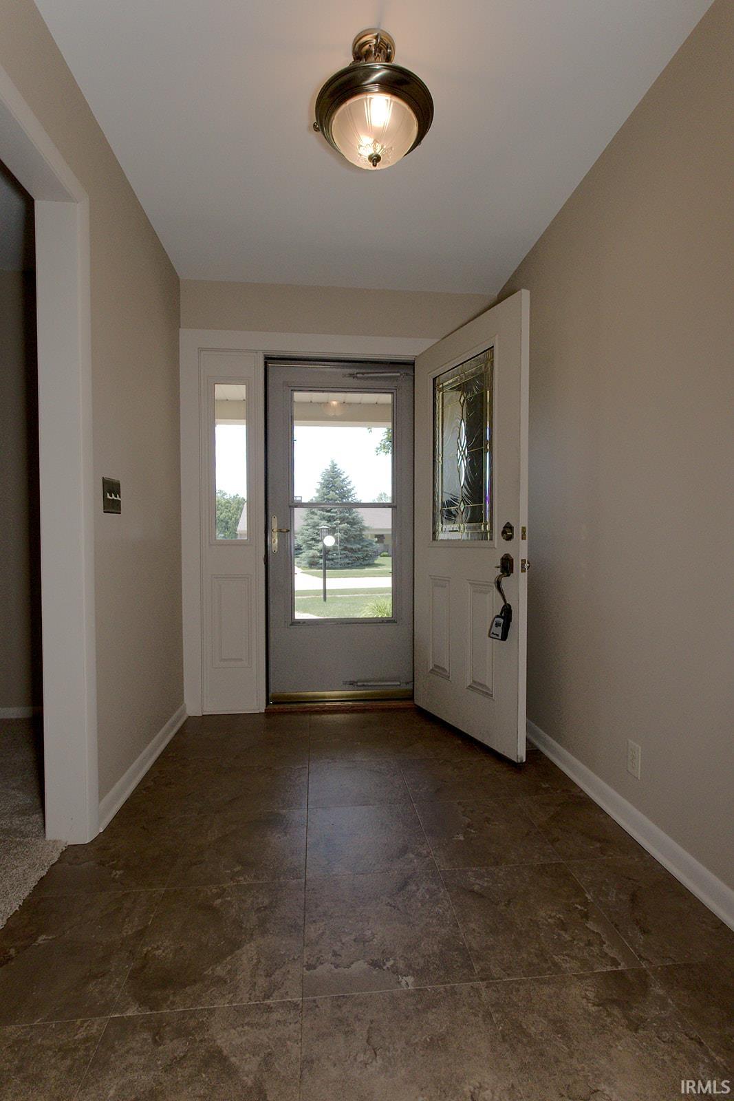 Entryway featuring tile-finish flooring, a decorative ceiling-mounted light fixture, and a front door with an integrated glass panel and side light