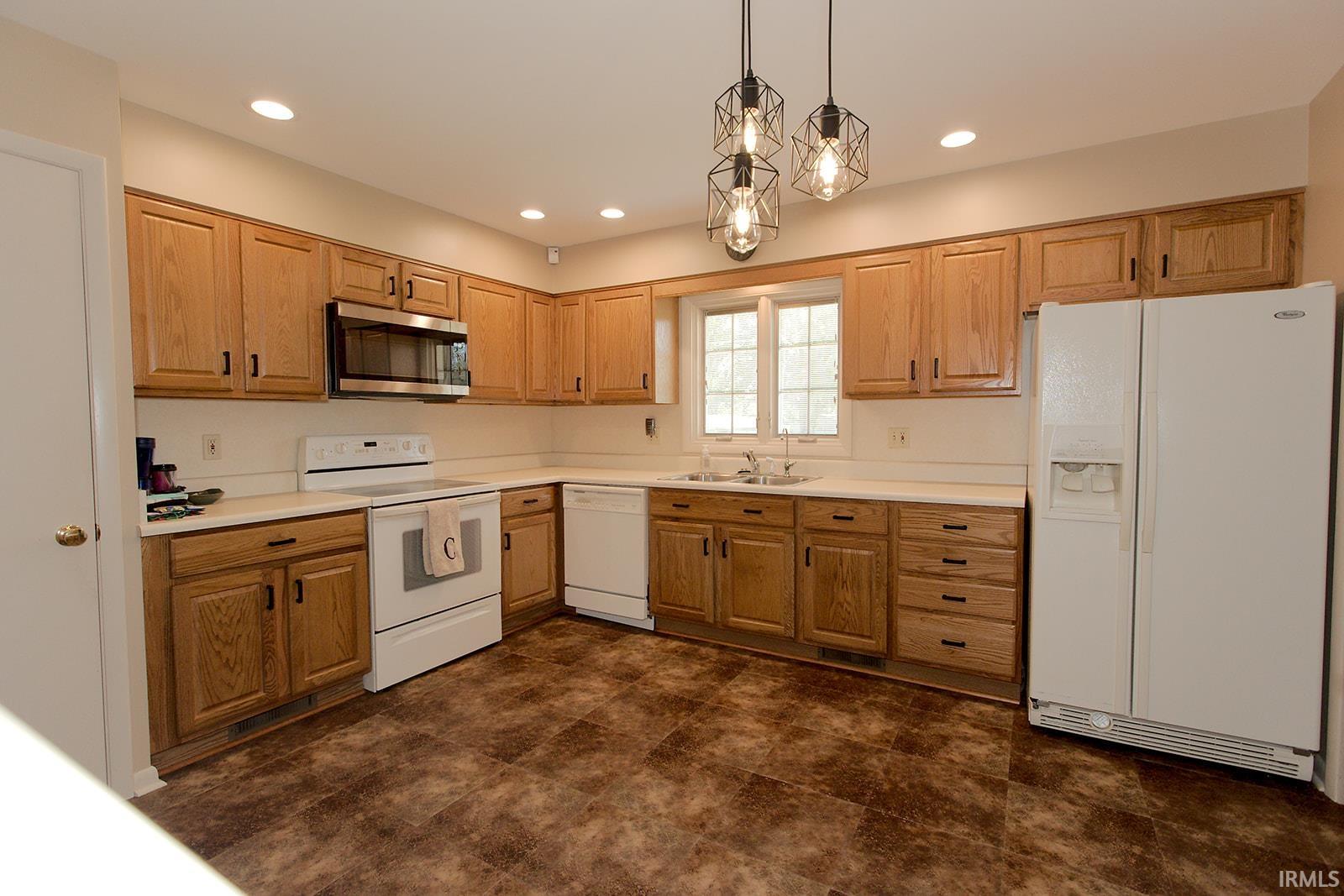 Spacious kitchen featuring wood cabinetry, white countertops, recessed lighting, and modern pendant fixtures