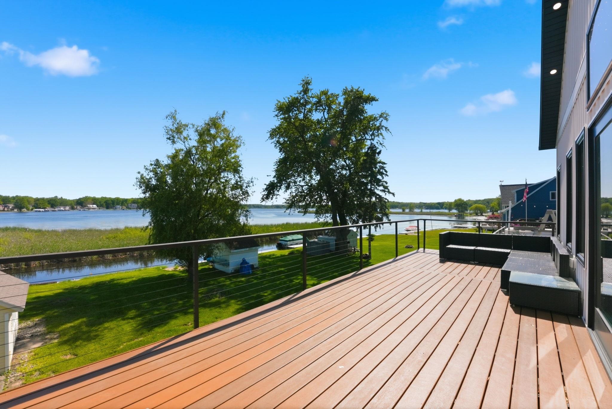 Expansive outdoor deck featuring wood-finish flooring, cable railings, and waterfront views