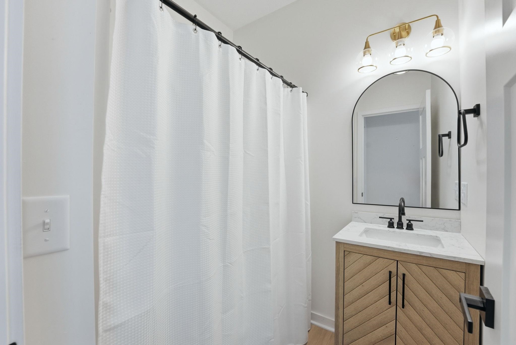 Bathroom featuring a wood-finish vanity with chevron detailing, a white countertop, and a rectangular undermount sink