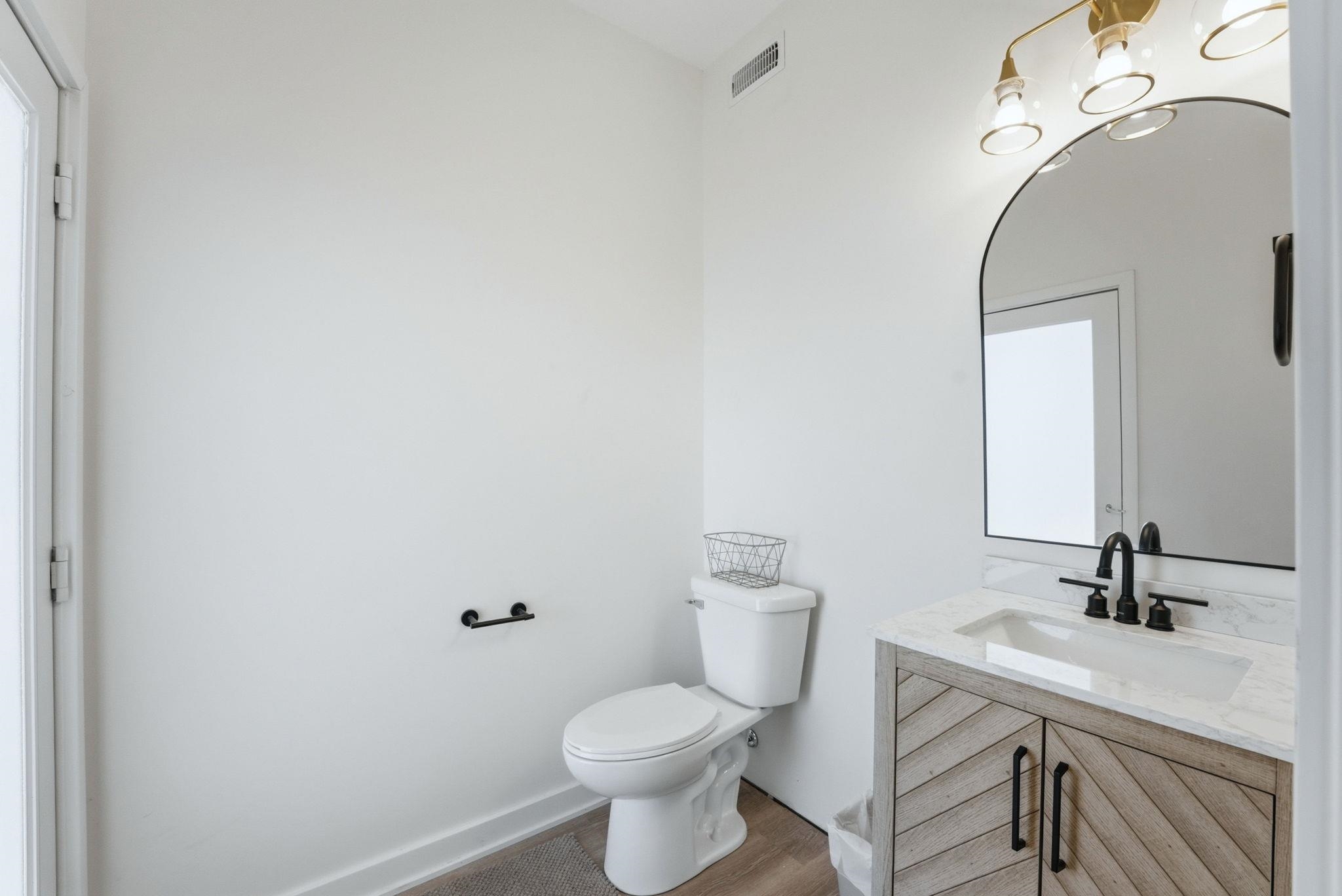 Bathroom vanity featuring a wood-finish cabinet with a chevron pattern, a white countertop with an undermount sink, and a matte black faucet