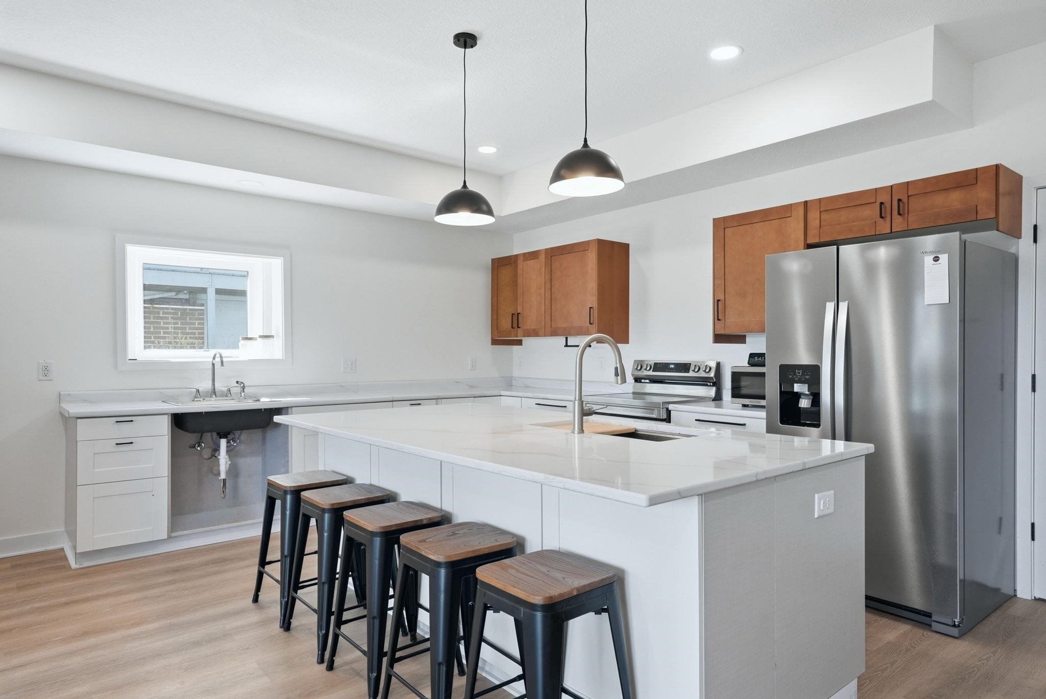Open-concept kitchen featuring light wood-finish flooring, white walls, and recessed lighting