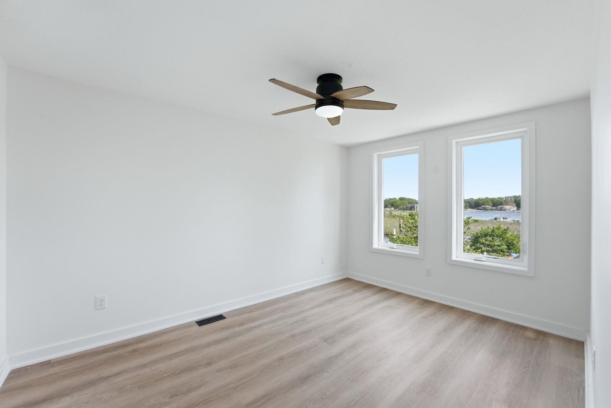 Bright room featuring wood-finish flooring, white walls, and a contemporary ceiling fan
