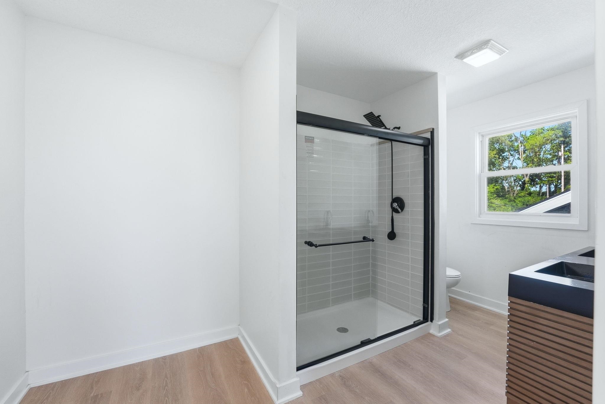 Modern bathroom featuring a walk-in shower with light gray subway tile, a black-framed glass enclosure, and matte black fixtures