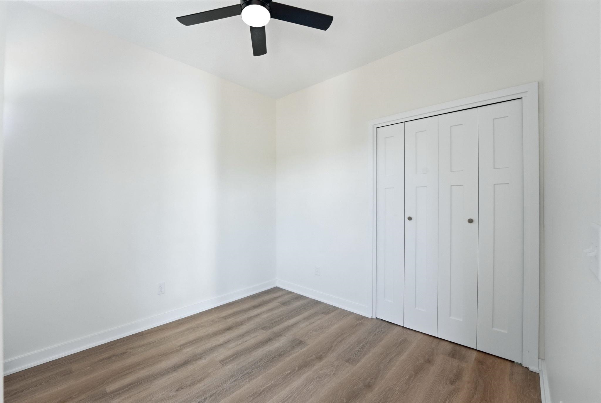 Neutral white walls with matching baseboards and wood-finish flooring