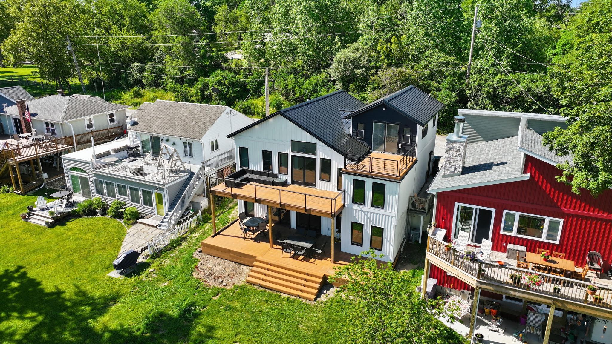 Modern black and white multi-level residence featuring multiple outdoor decks, a black metal roof, and large windows