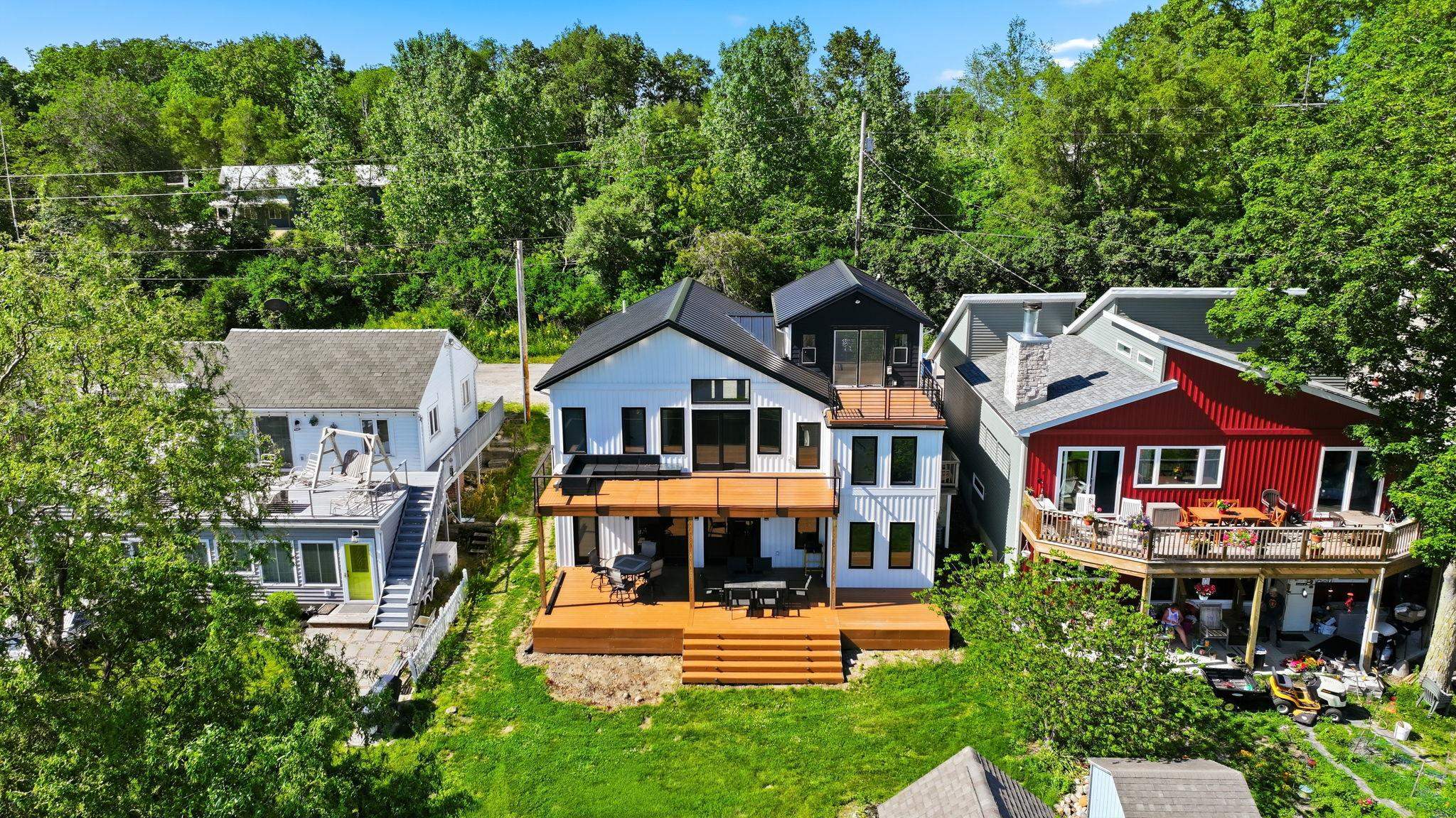 Modern vertical siding home featuring a multi-level deck, upper balcony, and a flat roofline