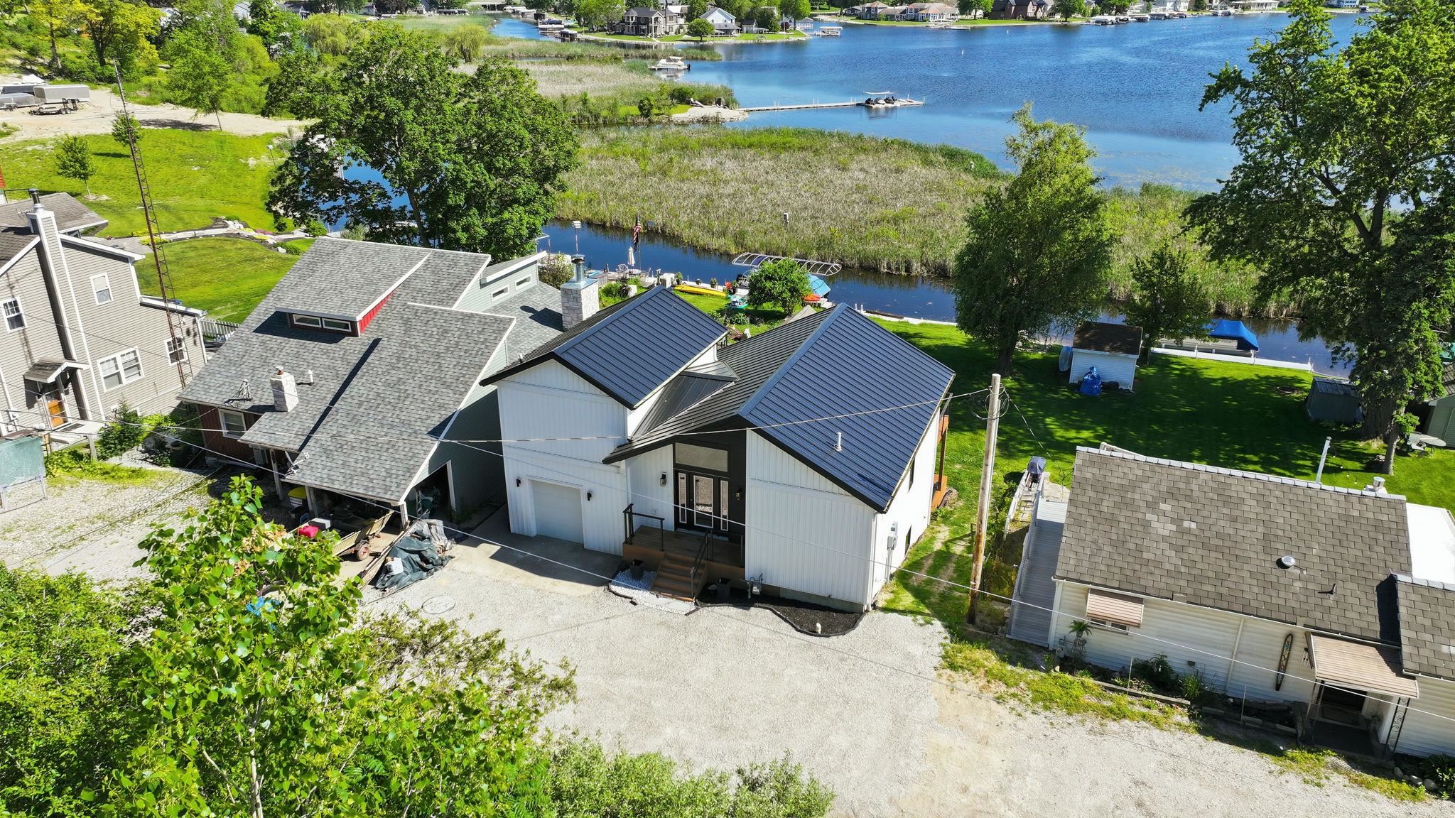 Contemporary architecture featuring white vertical siding, a dark metal roof, and an attached garage