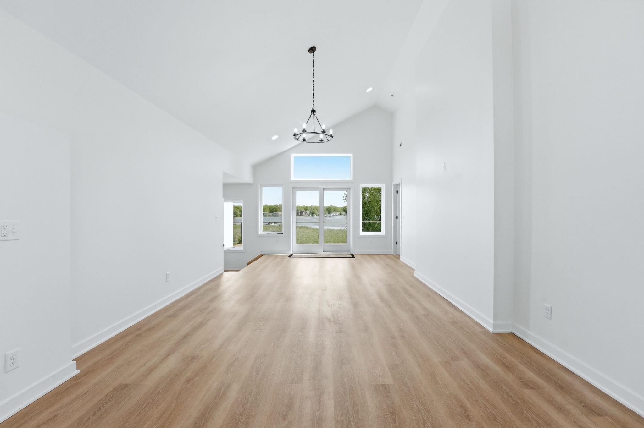 Spacious interior featuring high vaulted ceilings, light wood-finish flooring, and crisp white walls