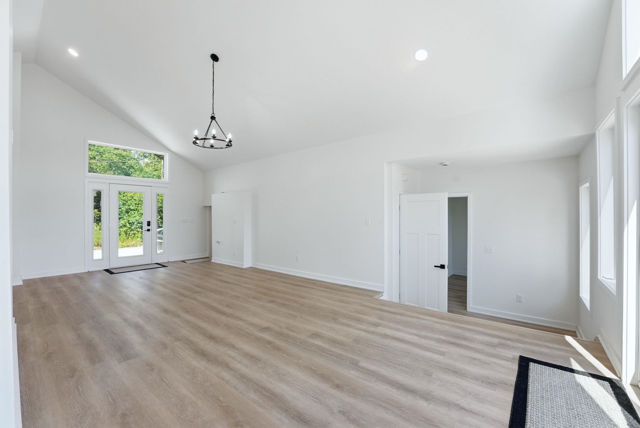 Spacious interior featuring wood-finish flooring, vaulted ceilings, and recessed lighting