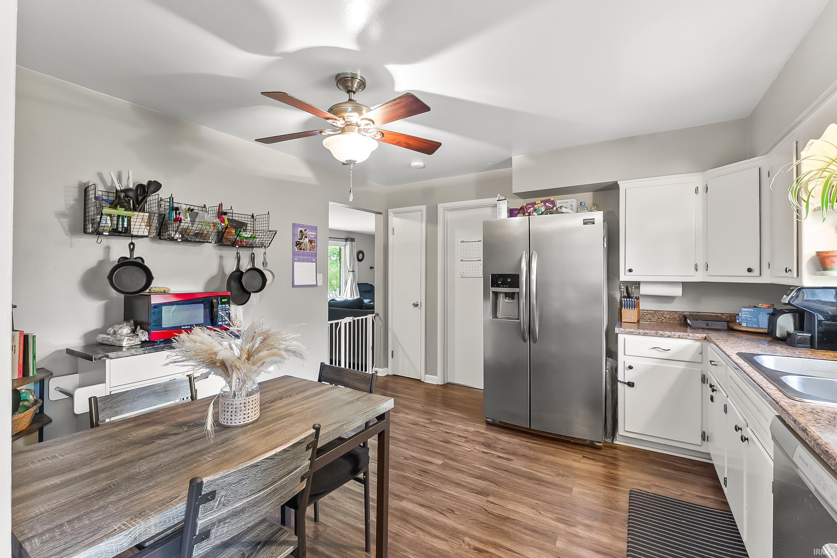 Open-concept kitchen with wood-finish flooring, white cabinetry, and stainless steel appliances