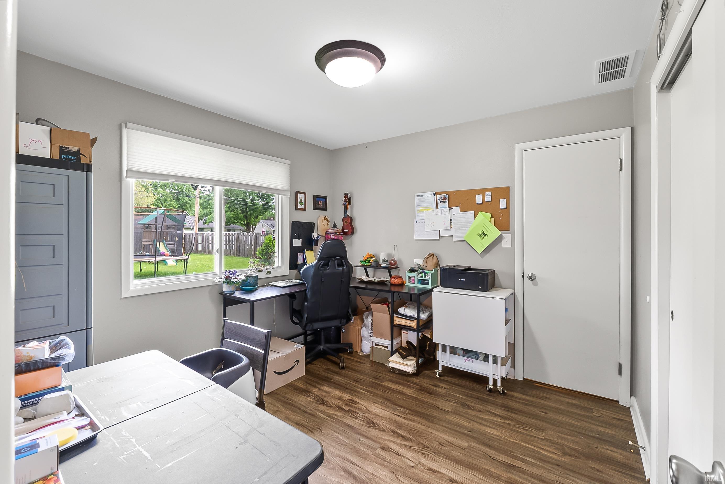 Room featuring wood-finish flooring, a double window with white blinds, and light gray walls