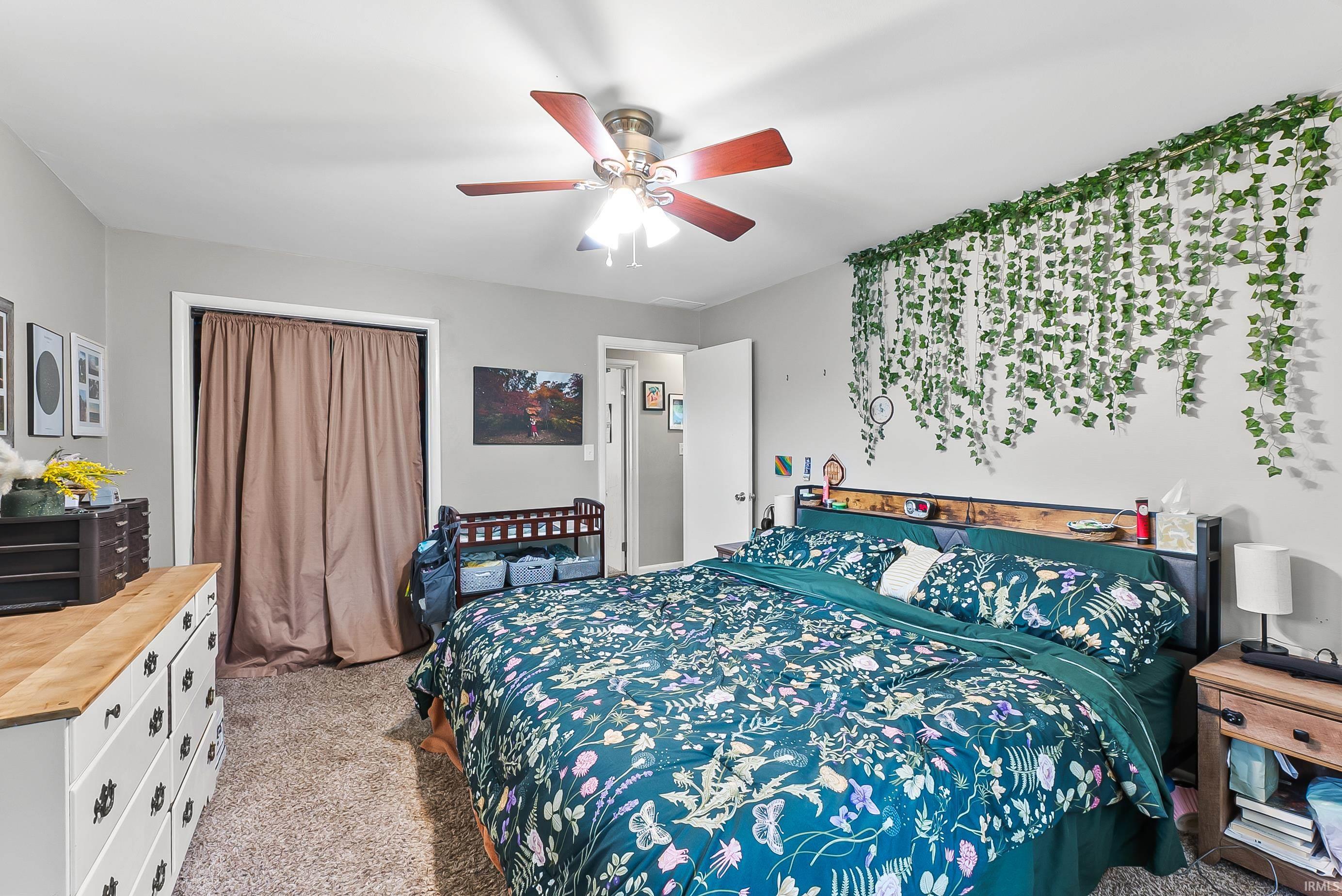 Bedroom featuring neutral wall paint, carpeted flooring, a ceiling fan, a closet with fabric doors, and an additional doorway
