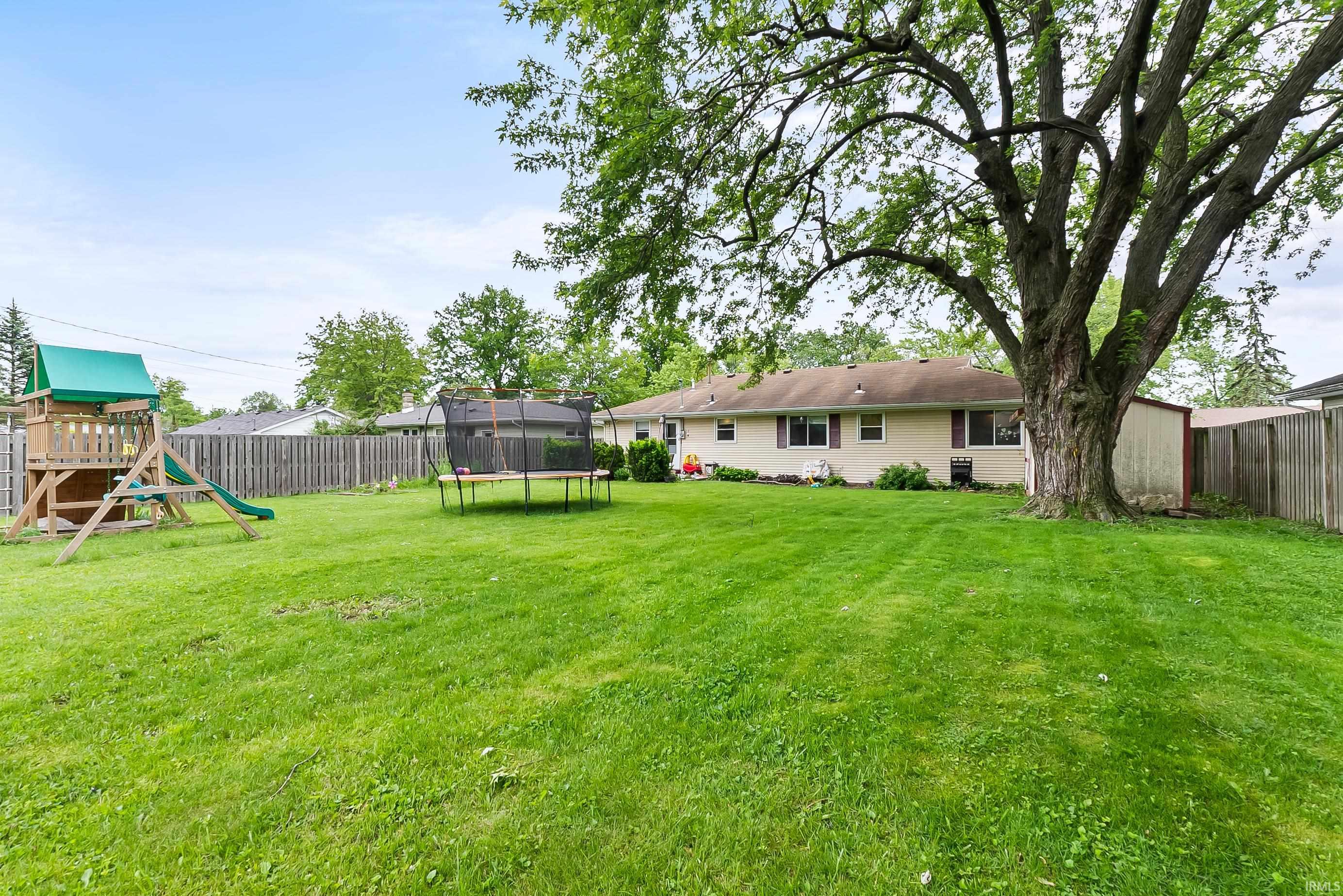Spacious green lawn with a large mature tree providing natural shade