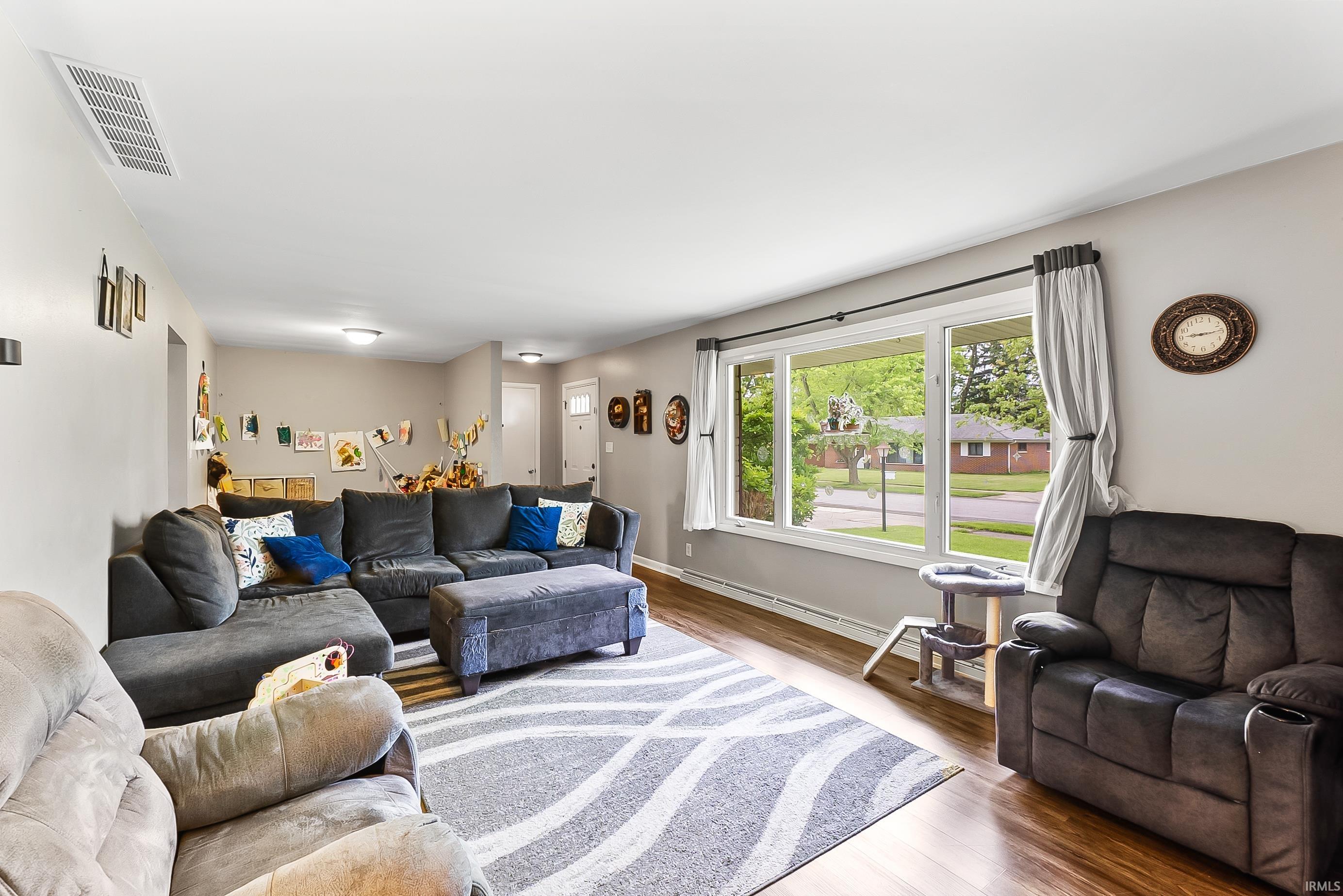 Spacious living area featuring wood-finish flooring, a large picture window, and light neutral wall paint