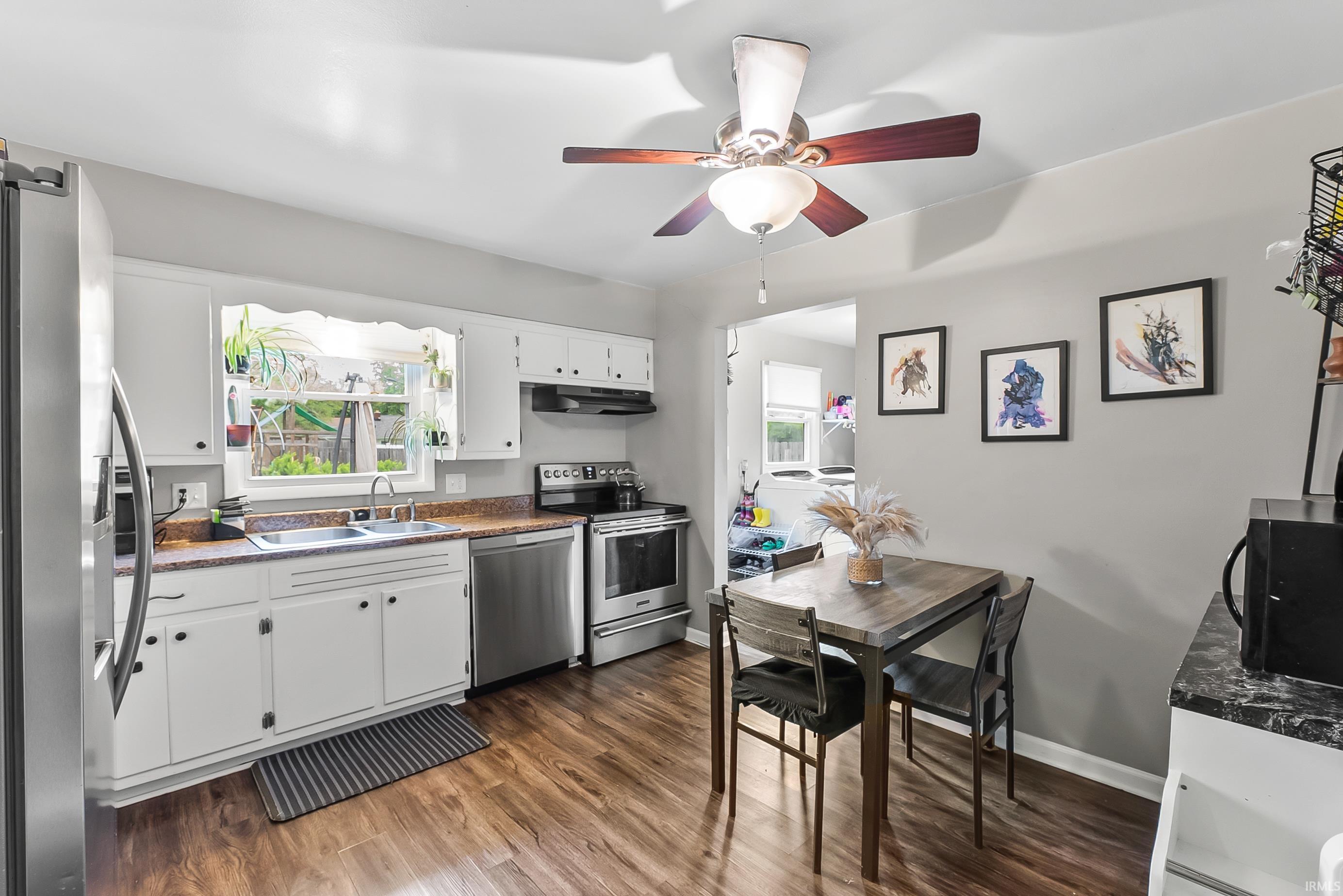 Kitchen featuring wood-finish flooring, white cabinetry, and stainless steel appliances