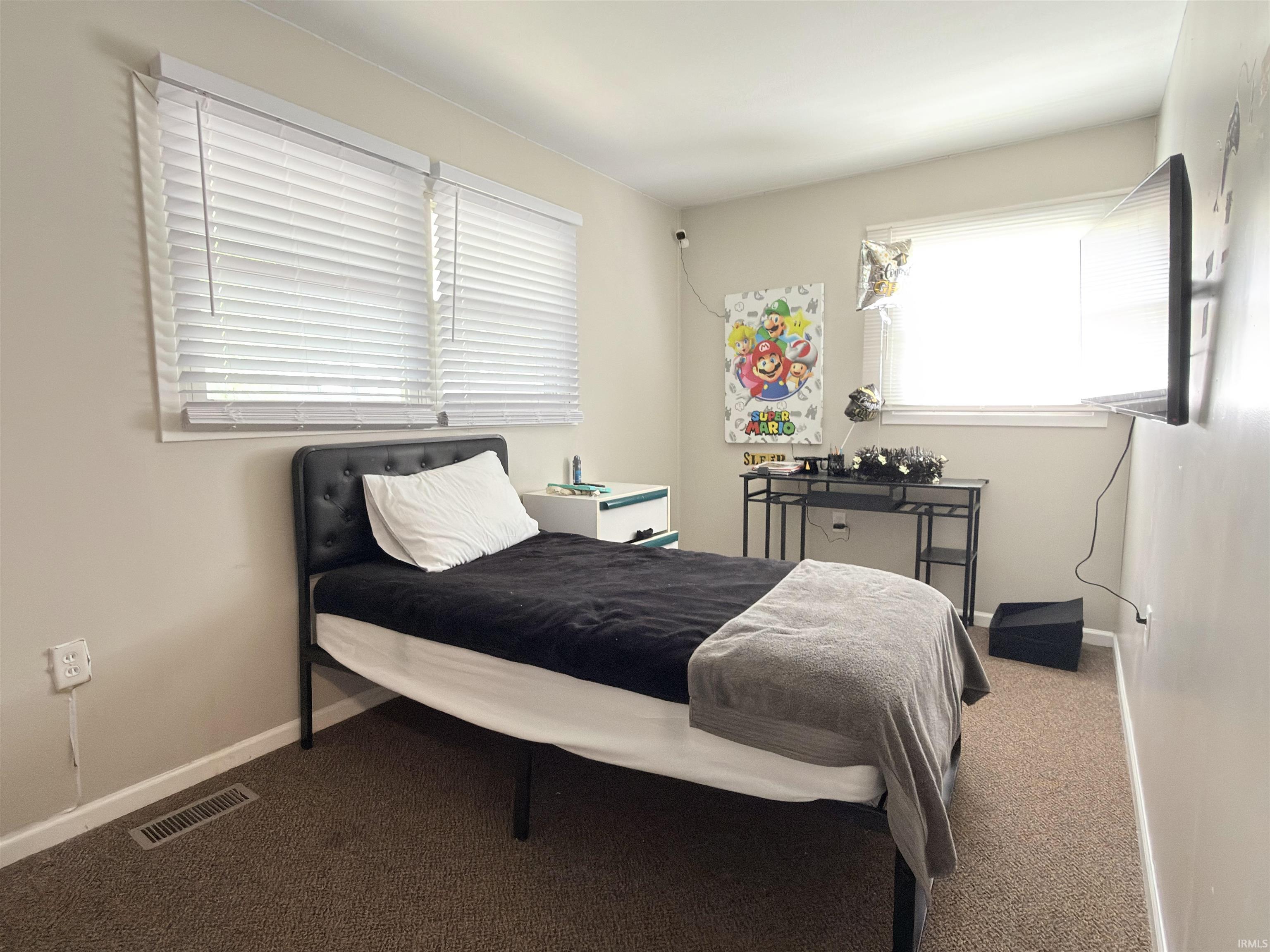 Bedroom featuring two windows with white blinds, neutral wall paint, and light brown carpeting