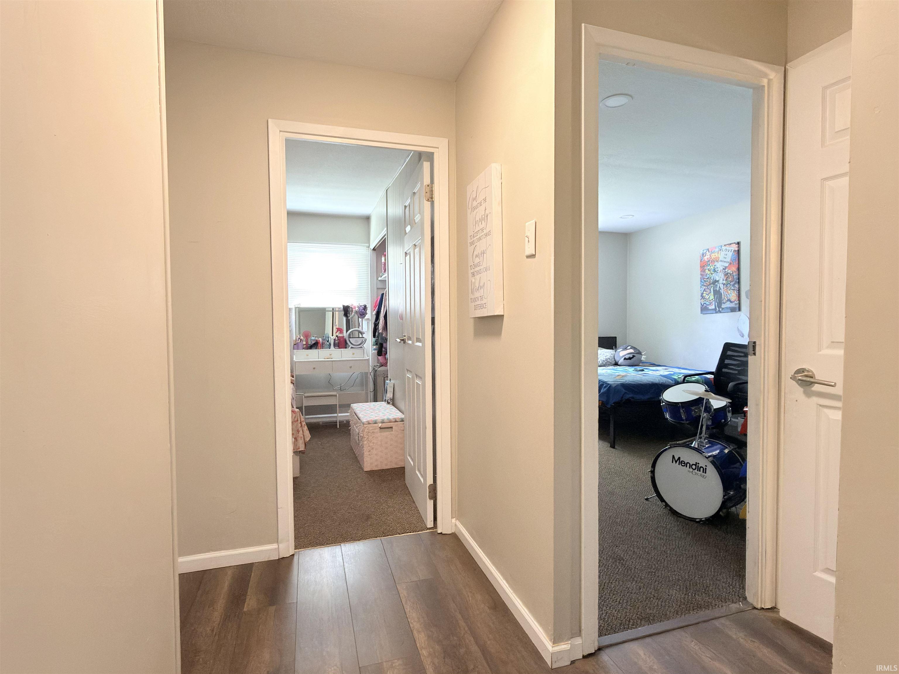 Hallway with wood-finish flooring providing access to two rooms