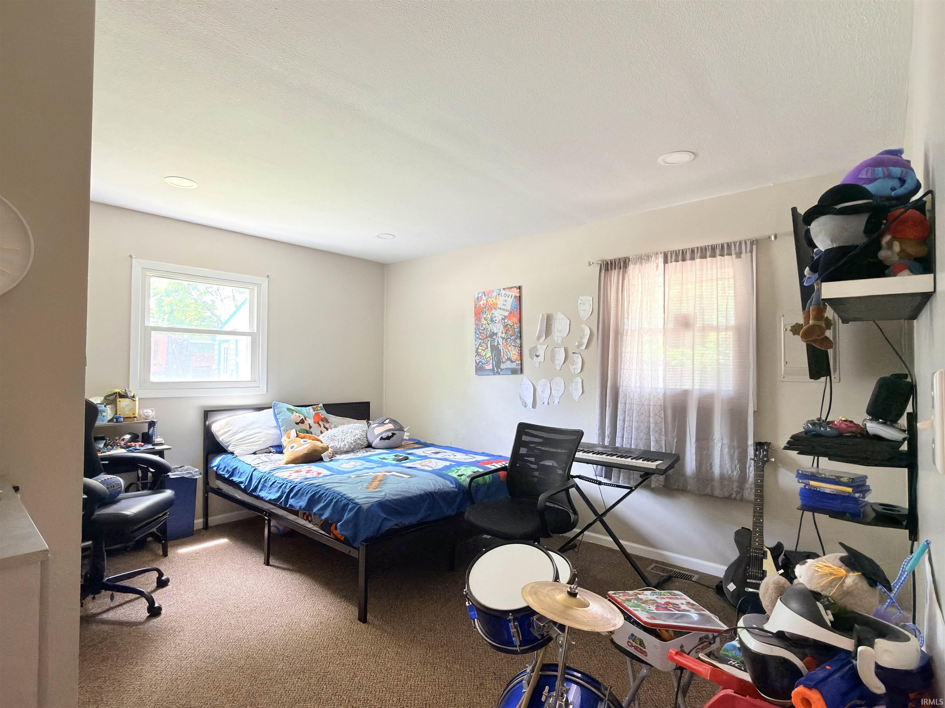 Bedroom with two windows, light tan walls, and recessed ceiling lights