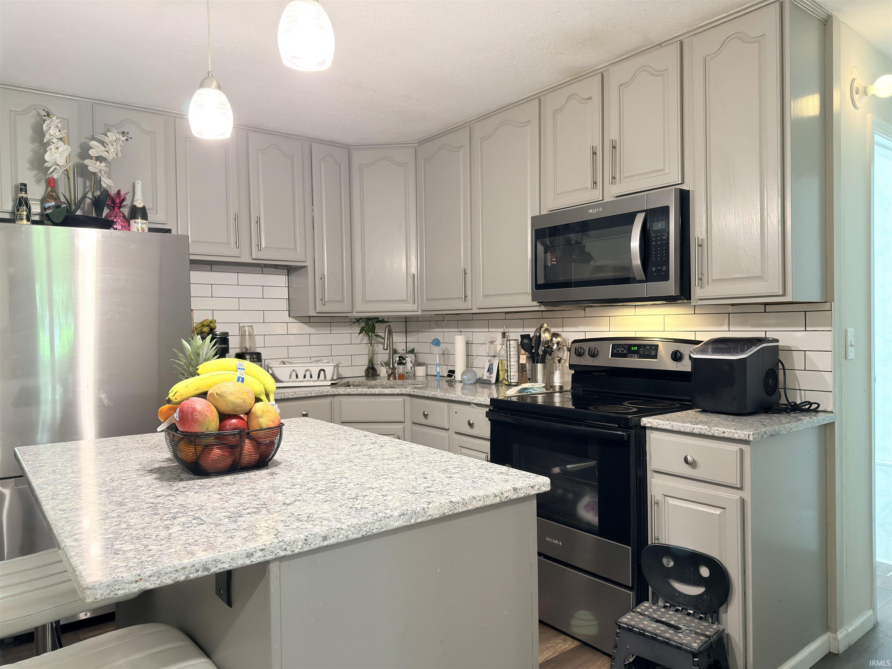 Kitchen featuring light gray cabinetry, white subway tile backsplash, and light-toned speckled countertops