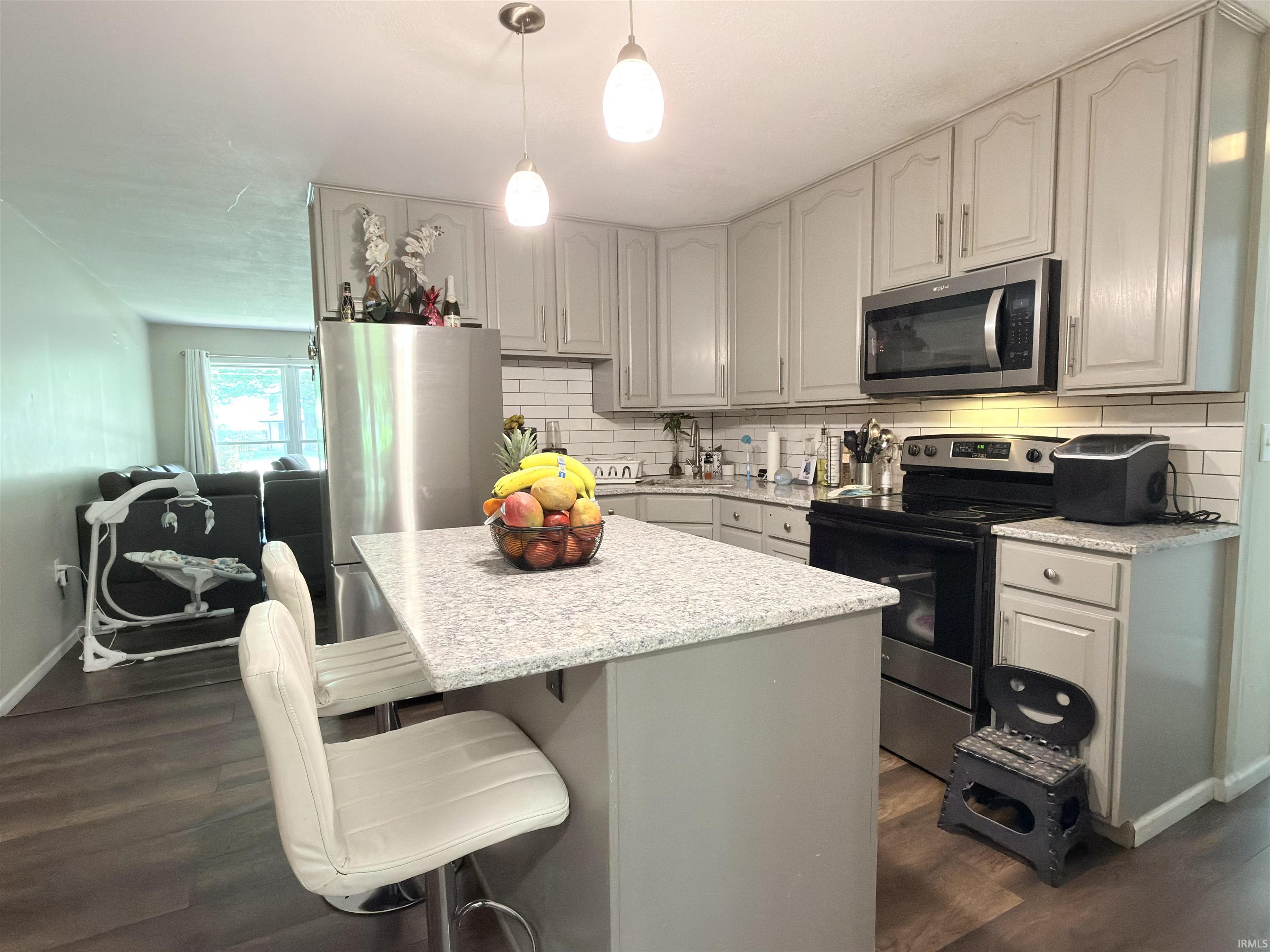 Kitchen featuring gray cabinetry, stainless steel appliances, a subway tile backsplash, and light-toned countertops