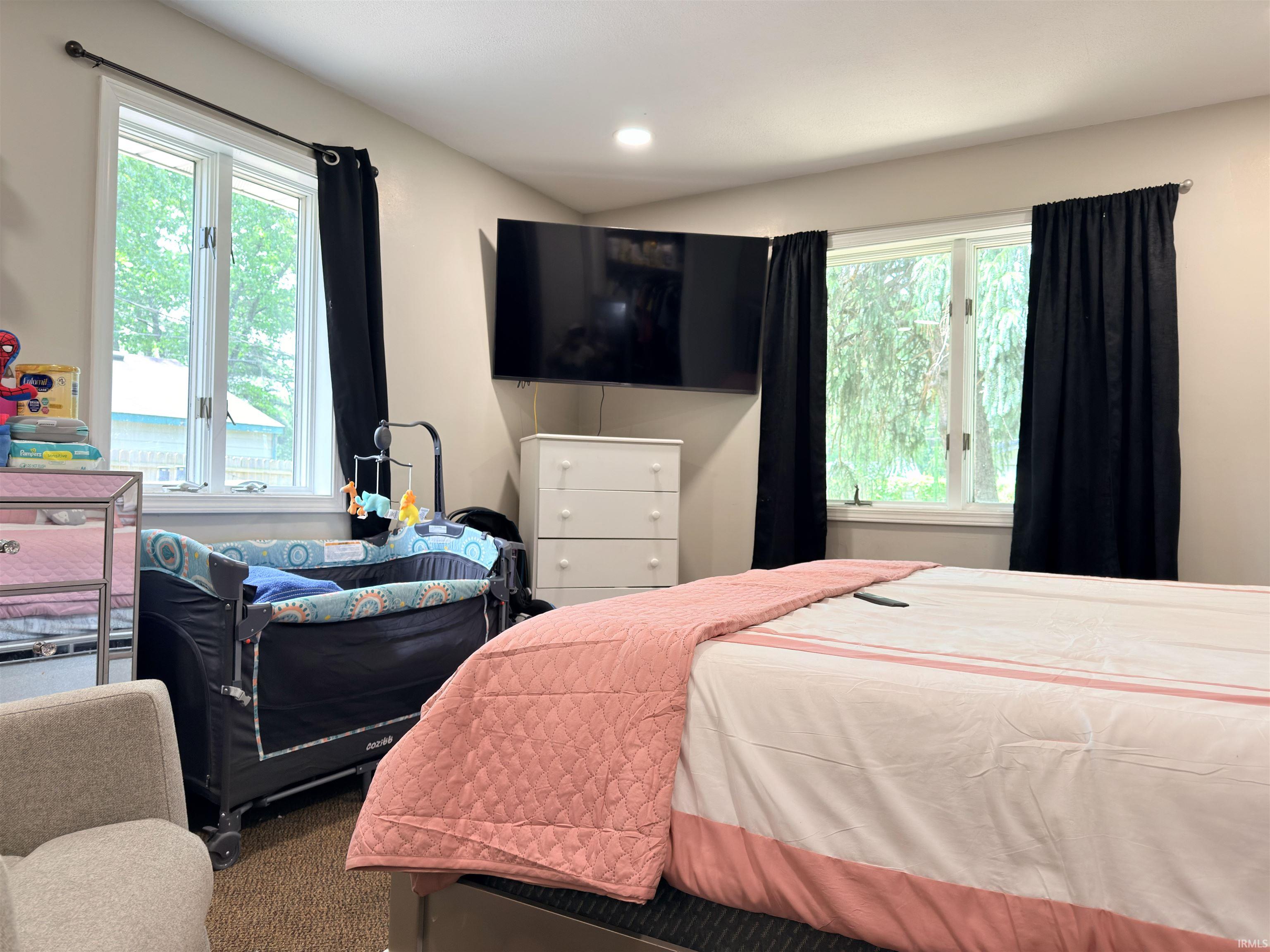 Bedroom featuring dual windows with white trim, recessed lighting, wall-mounted television, and light-toned wall paint