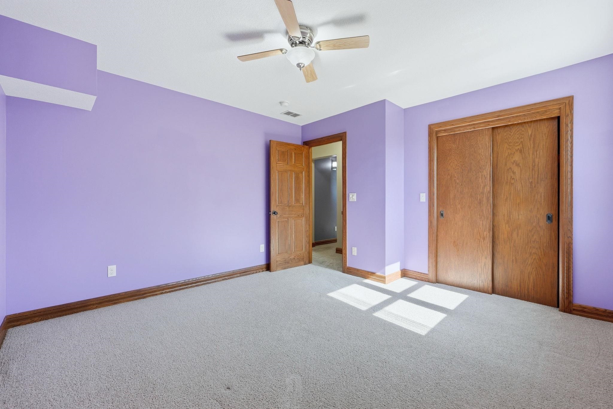 Spacious room featuring light lavender walls and light-colored carpeting