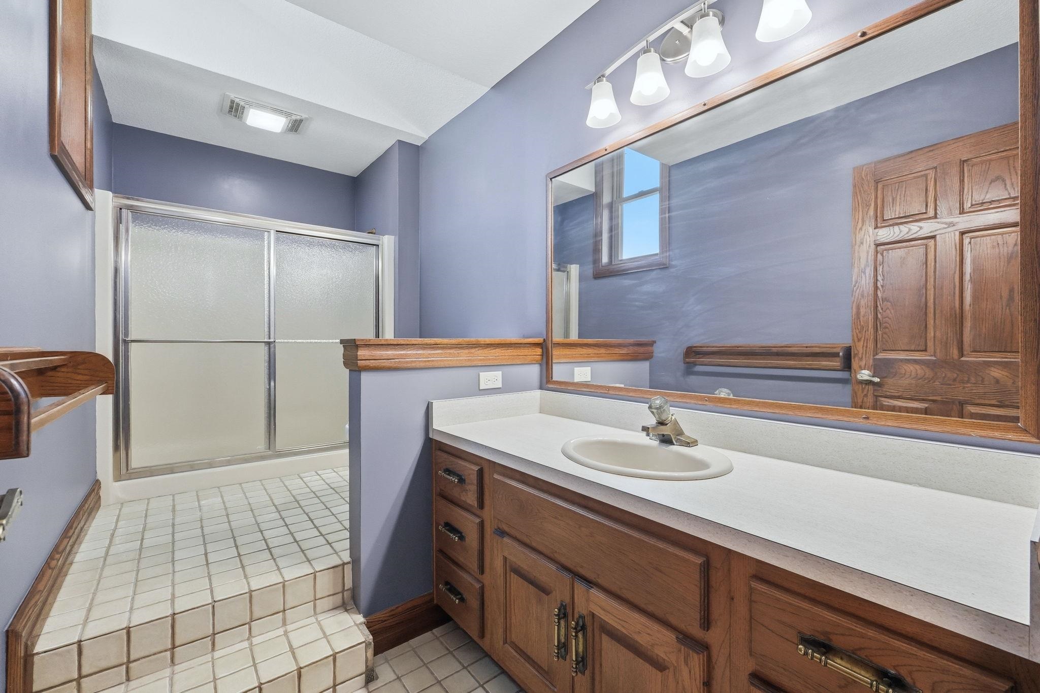 Bathroom featuring a wood vanity with a white countertop and an integrated oval sink