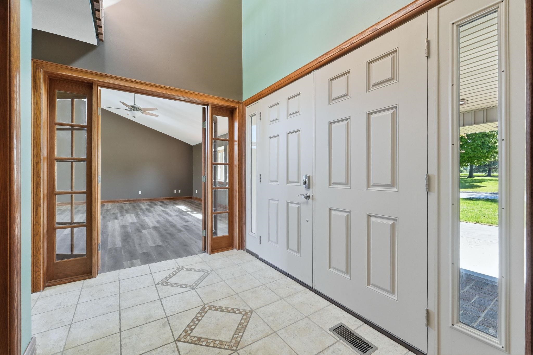 Entryway featuring tile flooring with decorative inserts, a paneled double door, and a sidelight window