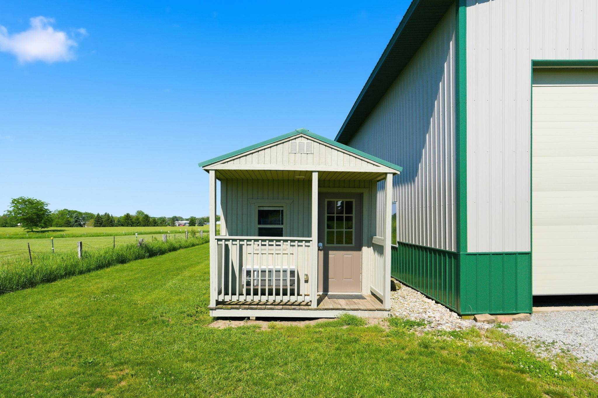 Detached outbuilding featuring a covered porch entrance and a large overhead door