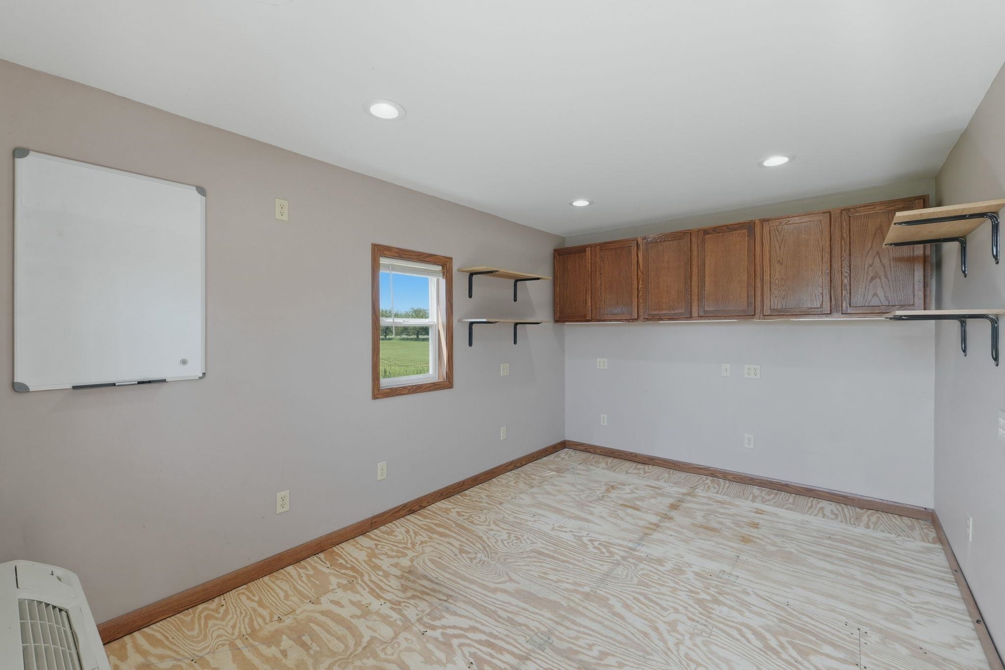 Room featuring recessed lighting, a window with wood trim, wood-finish baseboards, and plywood subflooring