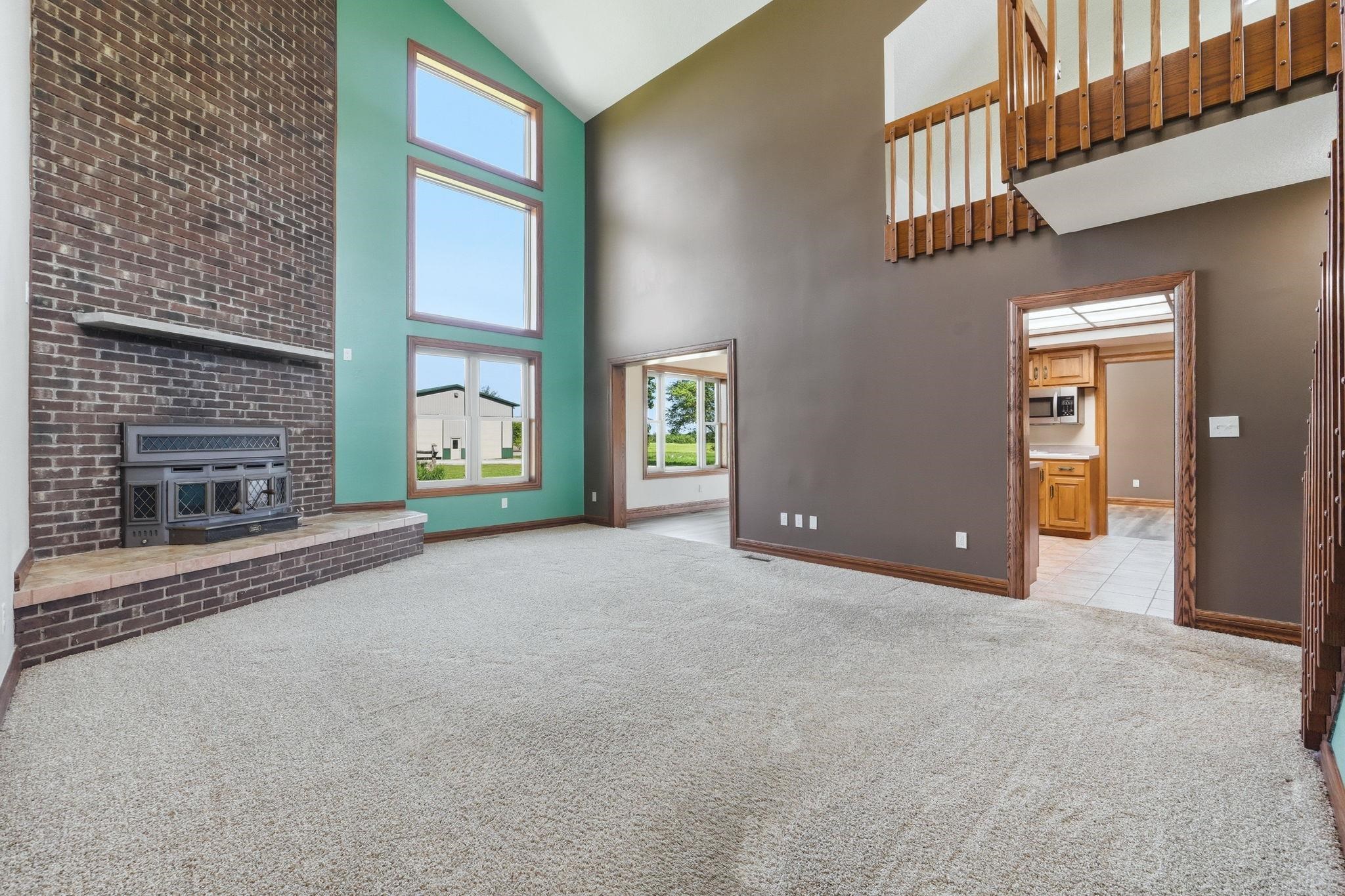 Great room featuring vaulted ceilings, a floor-to-ceiling brick fireplace with a raised hearth, and a multi-story window array