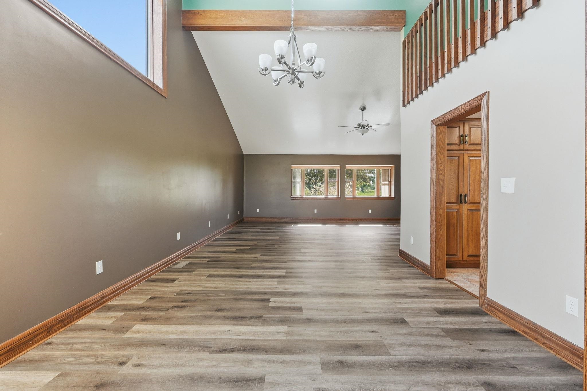 Bright, open living space featuring wood-finish flooring and a cathedral ceiling with exposed beam accents