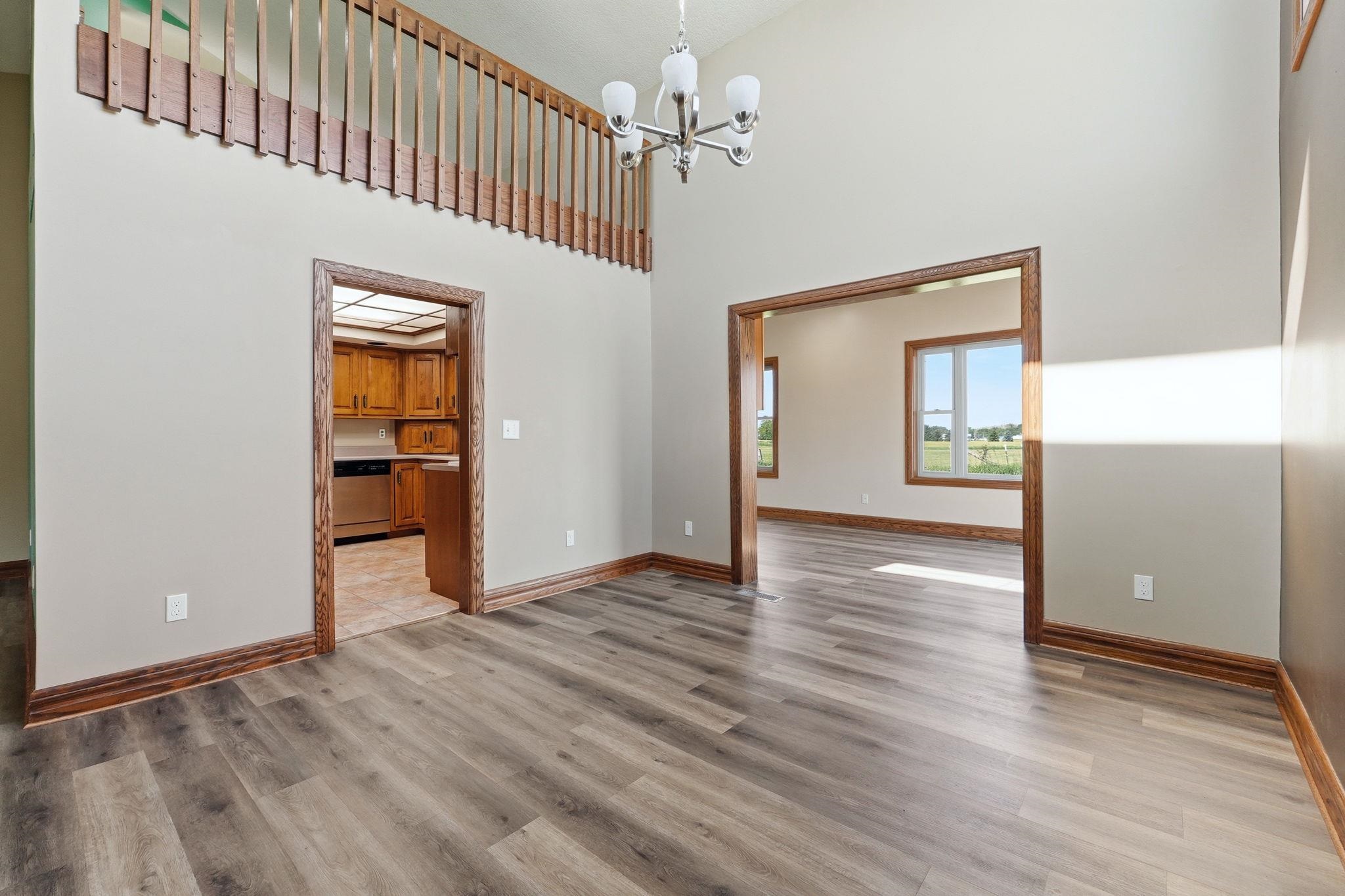 Vaulted ceiling with a contemporary chandelier, wood-finish flooring, and natural wood trim throughout